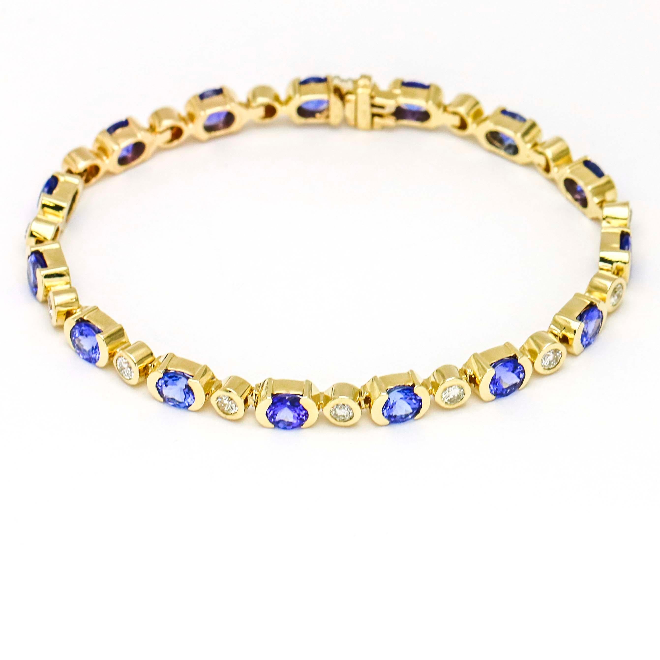 Tanzanite and diamond tennis bracelet crafted in 14 karat yellow gold. The bracelet is bezel set with alternating round Tanzanites and diamonds. Width, 5mm. Size large. 