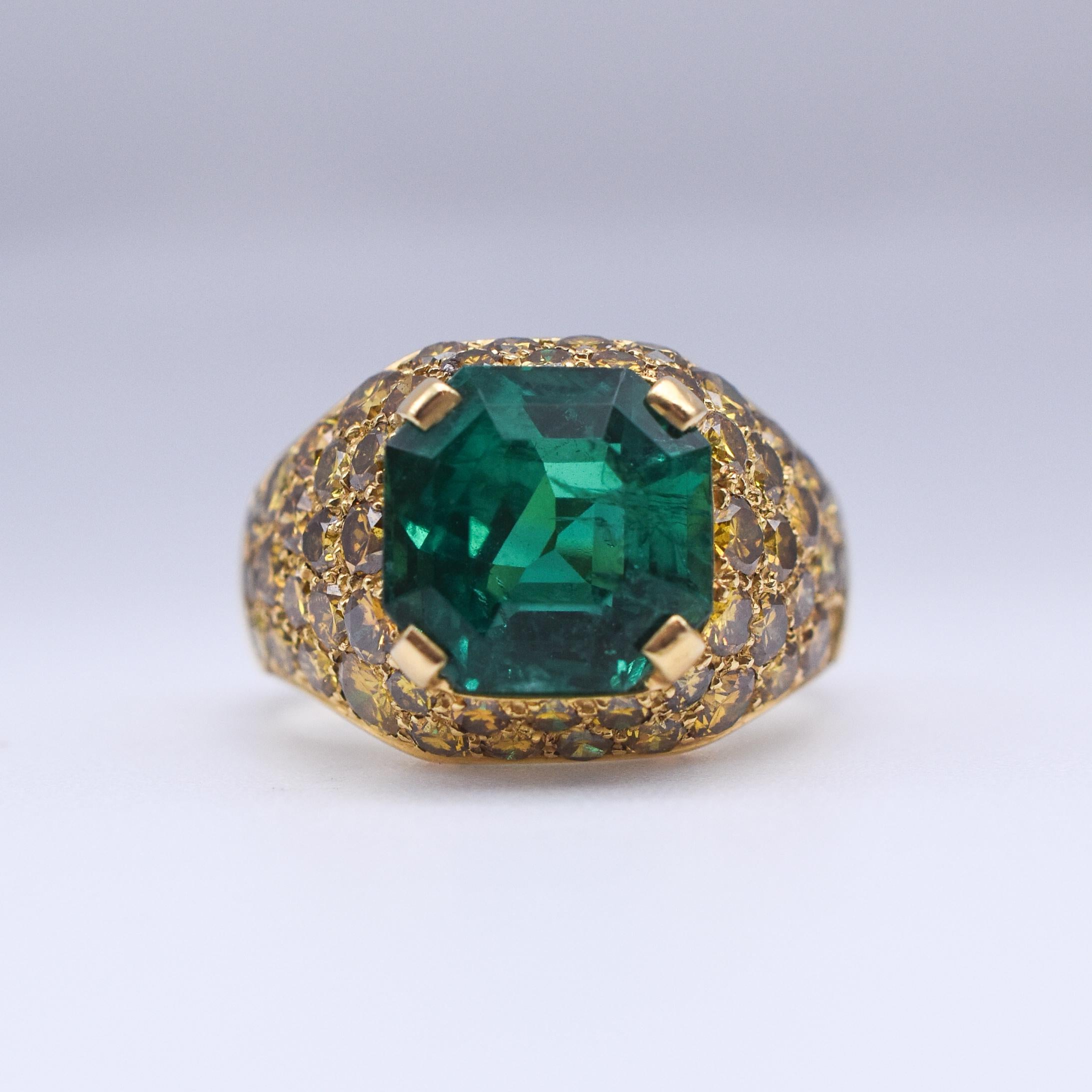 A sumptuous Emerald and Diamond Cocktail Ring, showcasing a splendid 4.70ct Colombian Emerald with moderate resin mounted on 18k Yellow Gold and further embellished with Fancy Yellow Diamonds. The ring is accompanied by a IGN certificate.