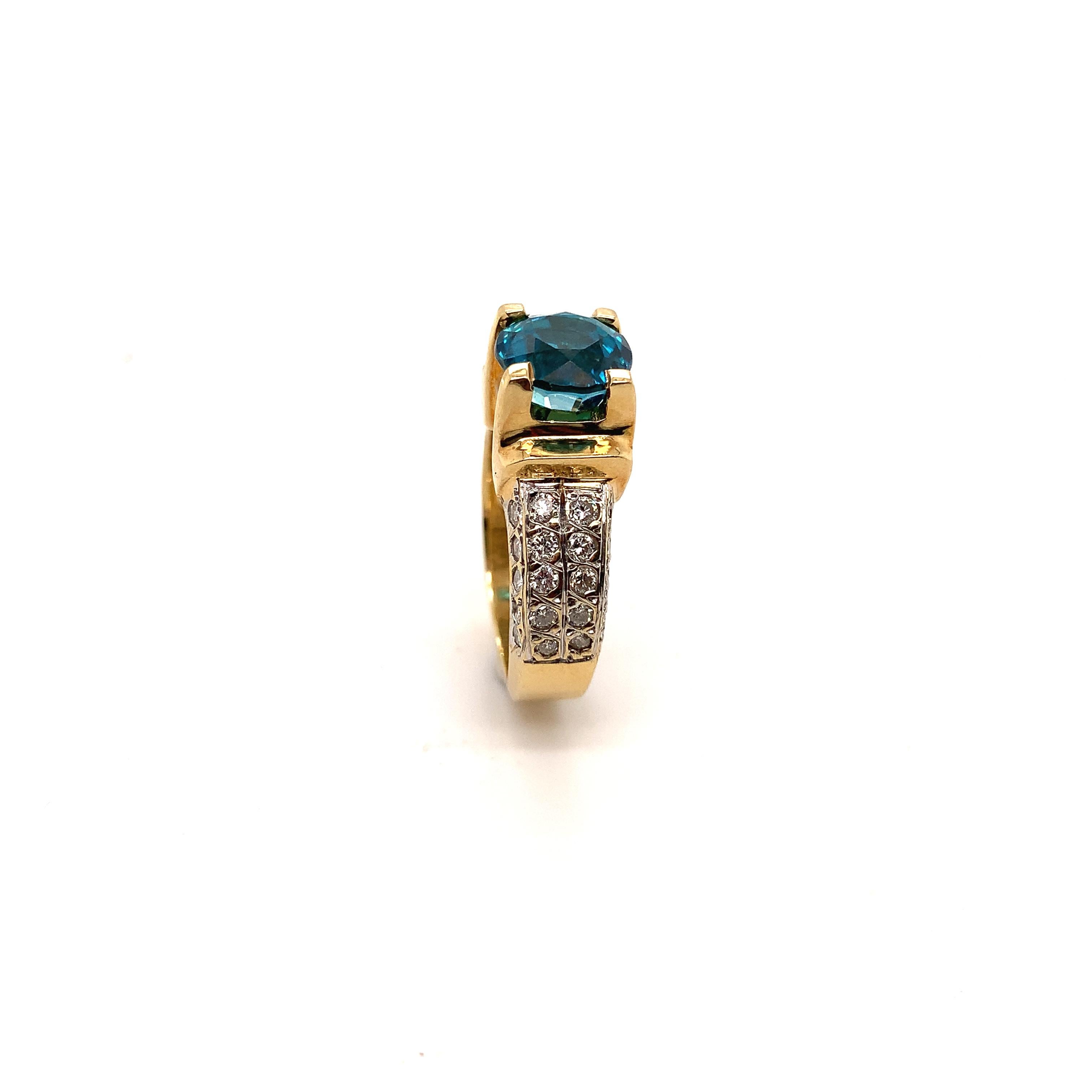This two tone 14-karat ring has a blue Zircon, December birthstone, as a center stone that weighs 4.71 carats,
it is a Cambodian step cut round, set in a yellow gold head, flanked on each side with 20 Diamonds, which are set in white gold, for a