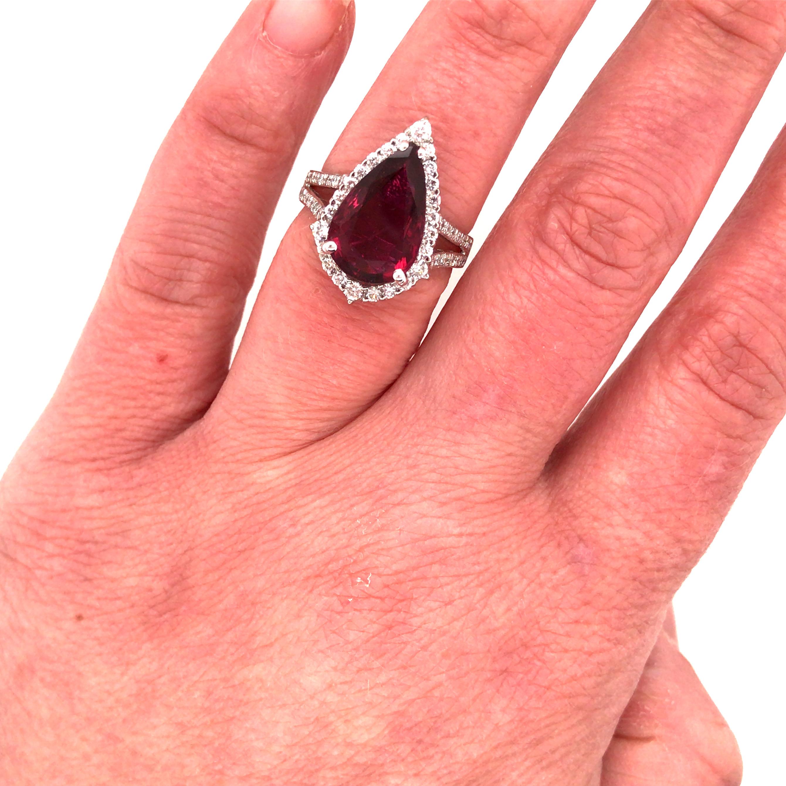 4.71 Carat Pear Shape Ruby and Diamond Halo Ring in 14K White Gold.  Round Brilliant Cut Diamonds weighing .80 carat total weight, G-H in color and VS in clarity are expertly set in the split shank and halo surrounding the Ruby Center.  The Ring
