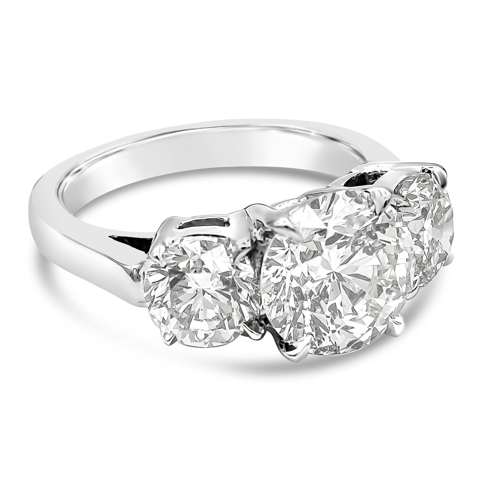 This classy and simple three stone engagement ring showcases a 2.70 carats brilliant round cut diamond certified by EGL as H color and SI2 in clarity, set in a four prong basket setting. Flanked by two round brilliant diamonds on each side weighing