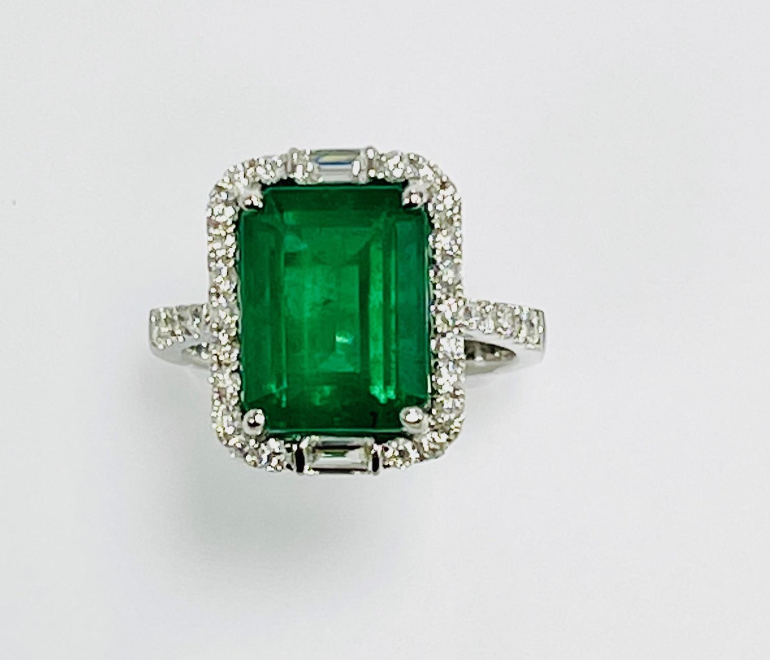 4.72 Carat Zambian emerald cut emerald set in 18k white gold ring with 0.84 Carat round and baguette diamond around it andhalf way on the shank..