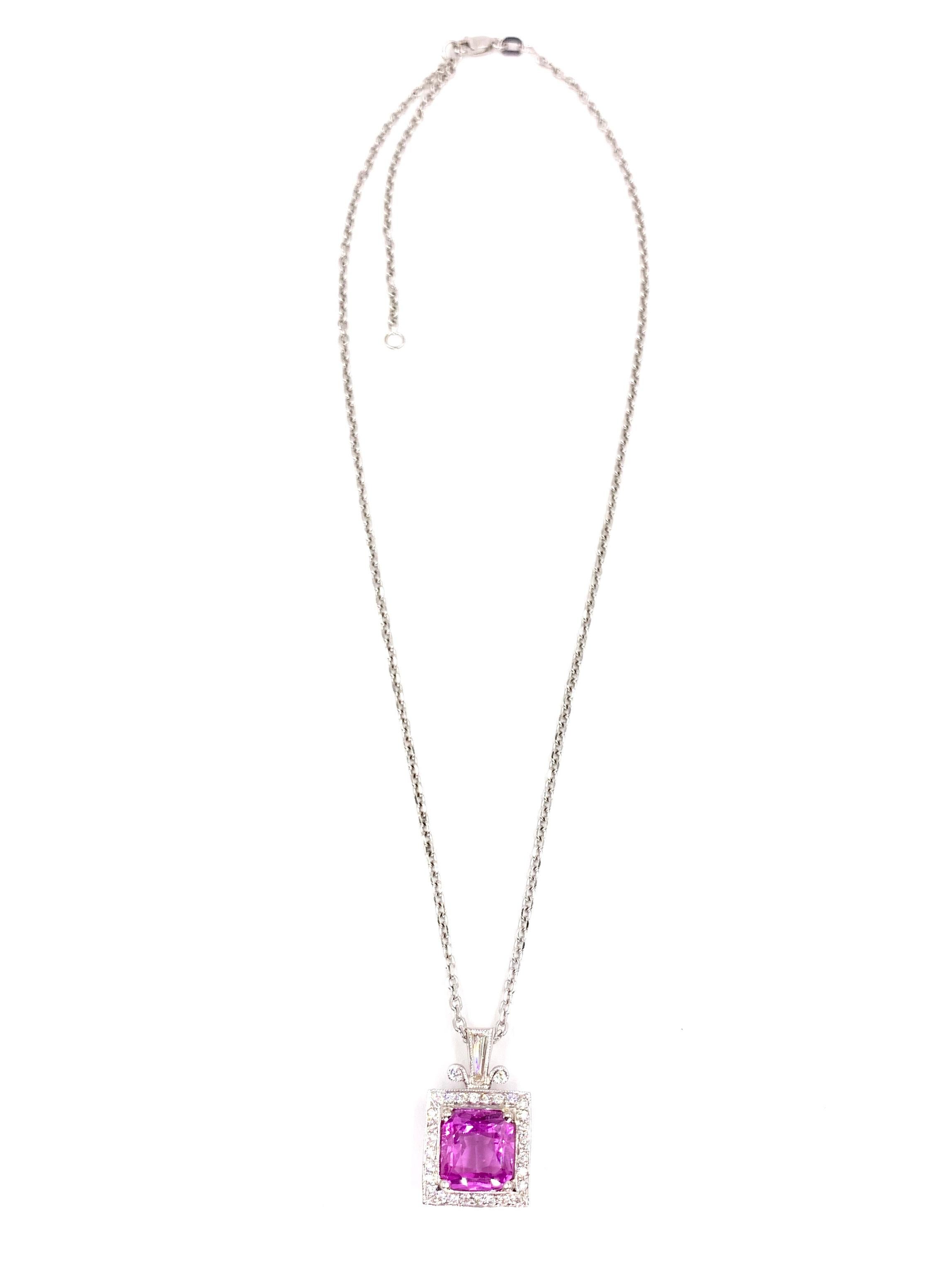 A cushion shape 4.74 carat intense pink sapphire is beautifully surrounded by an antiqued square halo of diamonds topped with a baguette cut adorned bale on this exquisite 18 karat white gold pendant. Pendant has a total diamond weight of 1 carat