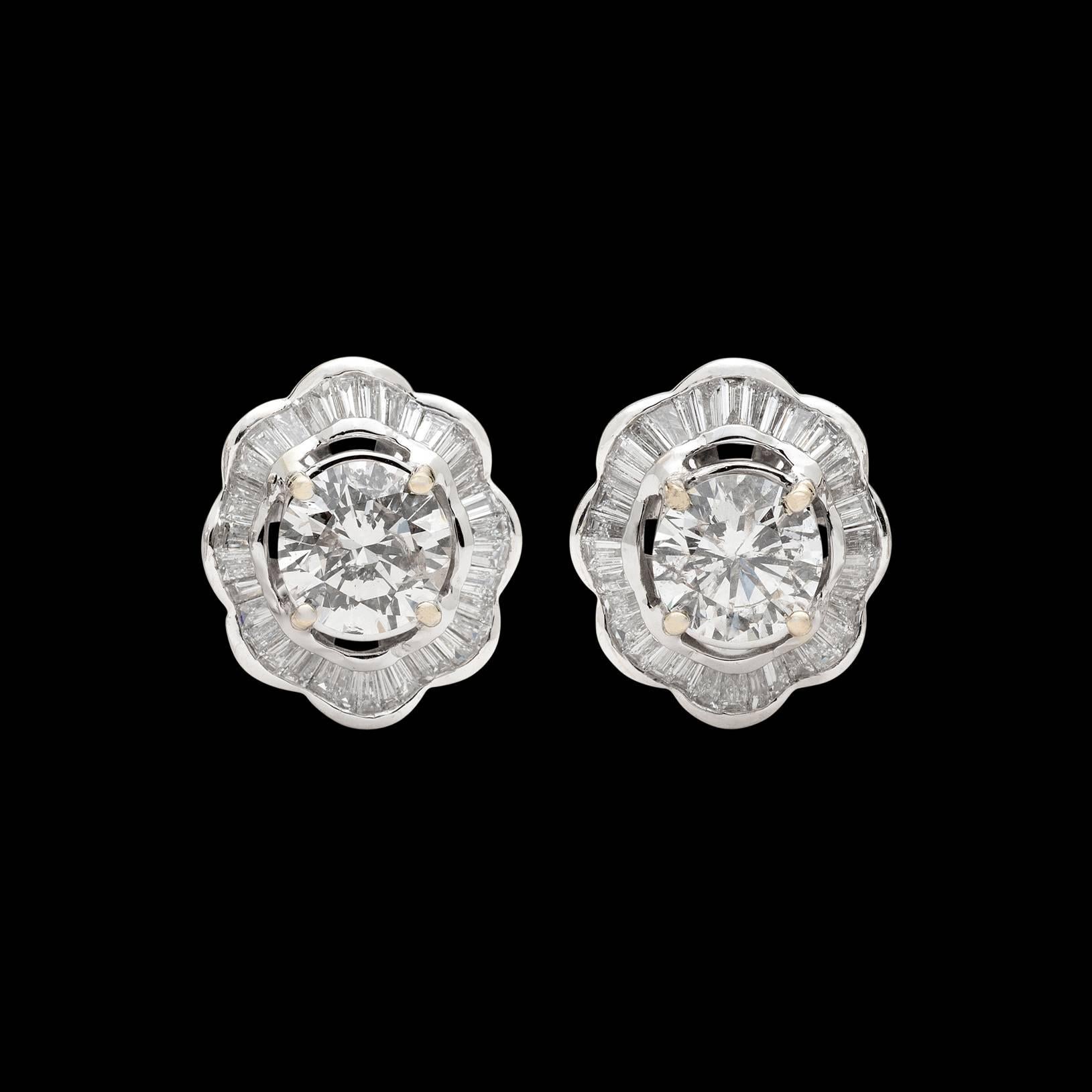 Better than simple studs, these classic 14k white gold earrings feature 2 Round Brilliant-Cut weighing together 3.35 carats, framed by waved swirls of baguette-cut diamonds, for a total diamond weight of 4.75 carats. The earrings weigh 8.0 grams.