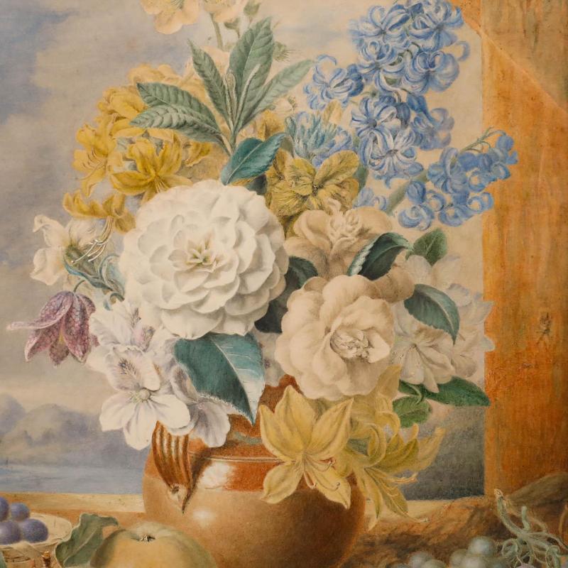 Cette délicate nature morte représente une composition florale élaborée dans un vase en céramique avec des fruits au premier plan, sur fond de montagne pittoresque. Bien présenté dans un cadre doré orné de détails moulés complexes et d'un vitrage au