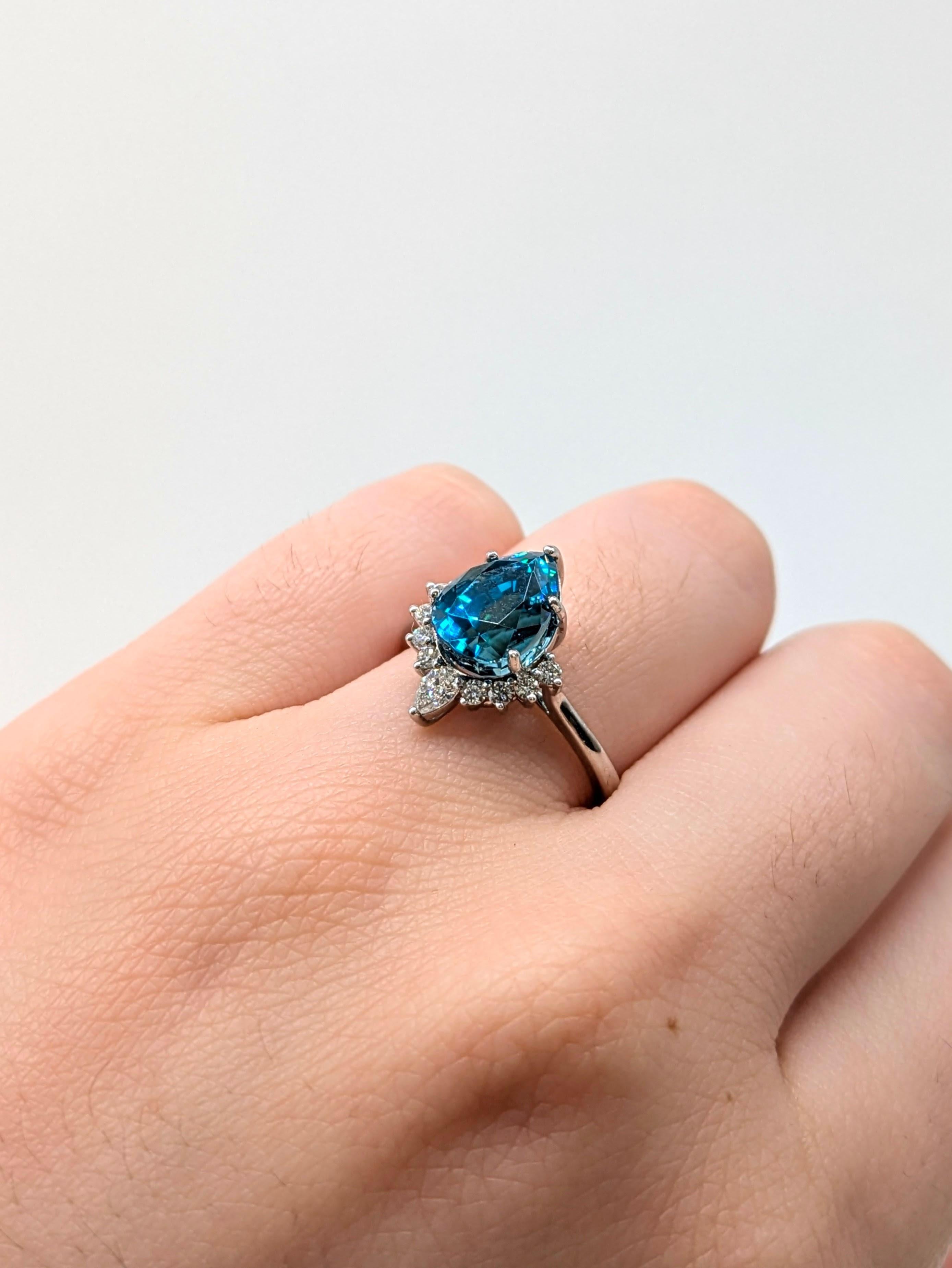 Un zircon bleu en forme de poire de 9x7 mm occupe le devant de la scène dans cette bague romantique de 4,75 carats, entourée de diamants naturels. Serti en or blanc massif 14 carats, son éclat raffiné et sa silhouette gracieuse en font une