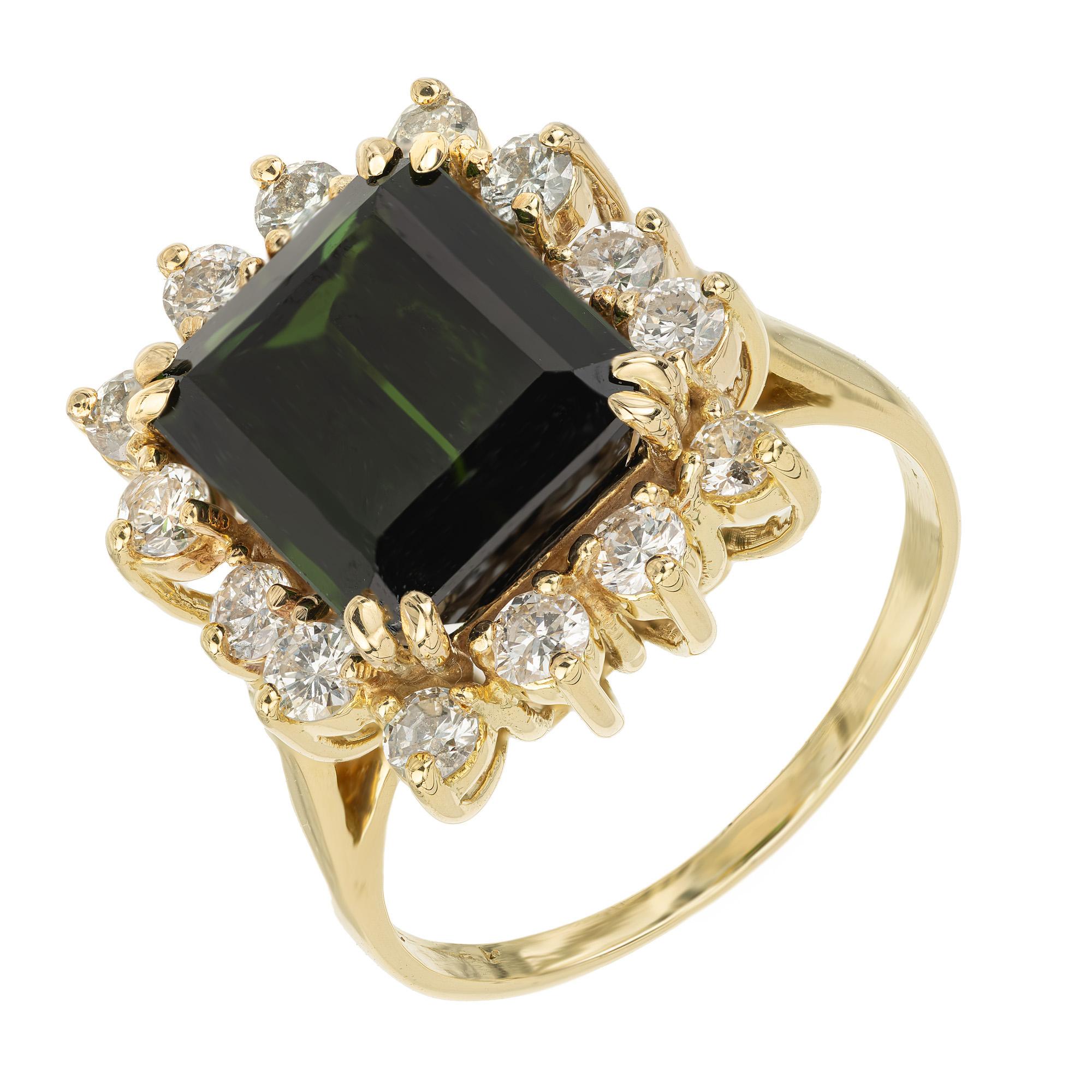 Introducing an exquisite marvel of 1970's design and craftsmanship, the 4.76ct emerald cut tourmaline and diamond cocktail ring. The center of this mounting features a rich green tourmaline, its vibrant hue surrounded by a dazzling halo of 14 round