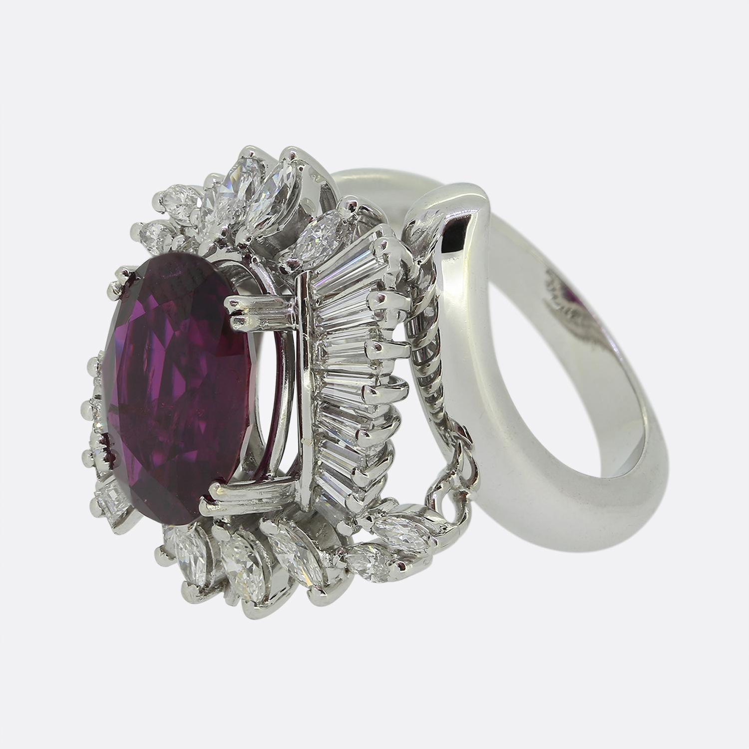 Hier haben wir einen auffälligen Statement-Ring mit einem fesselnden sattroten Rubin in der Mitte der Vorderseite. Der Hauptstein sitzt leicht erhöht in einer Fassung mit vier Zacken auf einem geschwungenen Hintergrund aus strahlend weißen Diamanten