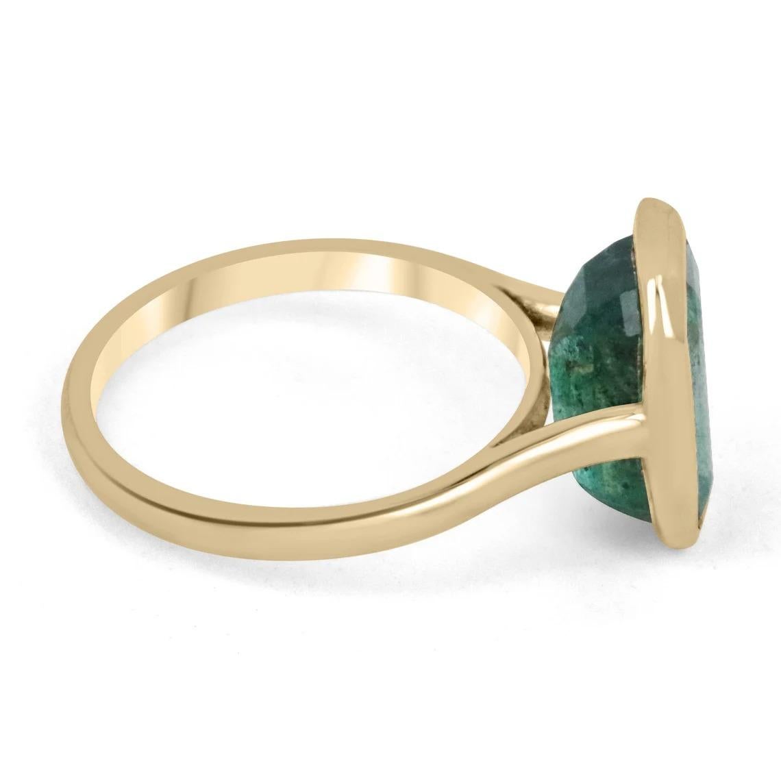 Displayed is a stunning emerald solitaire engagement or right-hand ring in 14K yellow gold. This gorgeous solitaire ring carries a 4.76-carat emerald in a bezel setting. Fully faceted, this gemstone showcases excellent shine and beautiful, dark