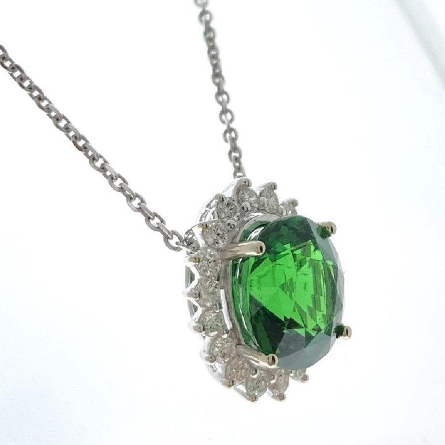 Questo affascinante ciondolo presenta una vibrante tsavorite ovale verde da 4,79 carati, rinomata per la sua lussureggiante tonalità verdeggiante e l'eccezionale purezza. La tsavorite è elegantemente incastonata in una montatura in oro bianco 14