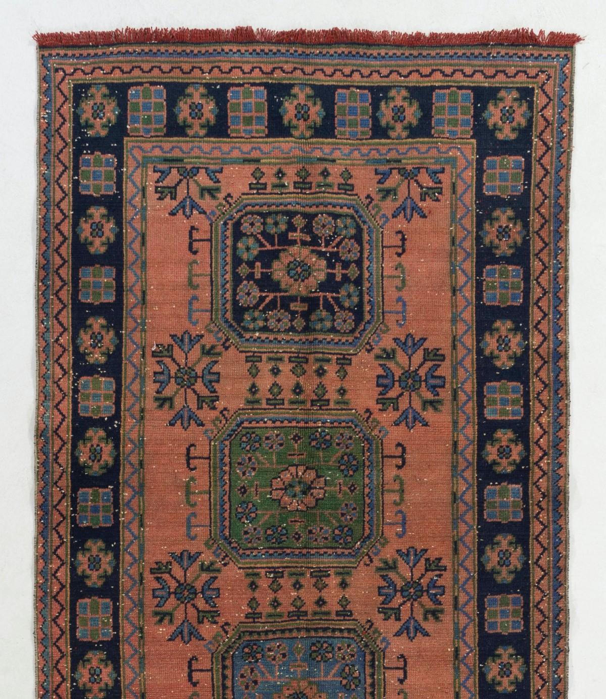 A gorgeous vintage Turkish runner rug, hand-knotted with low wool pile on cotton foundation. It features geometric medallions decorated with floral motifs. It is in good condition, professionally-washed and sturdy. Measures: 4.7 x 11 ft.