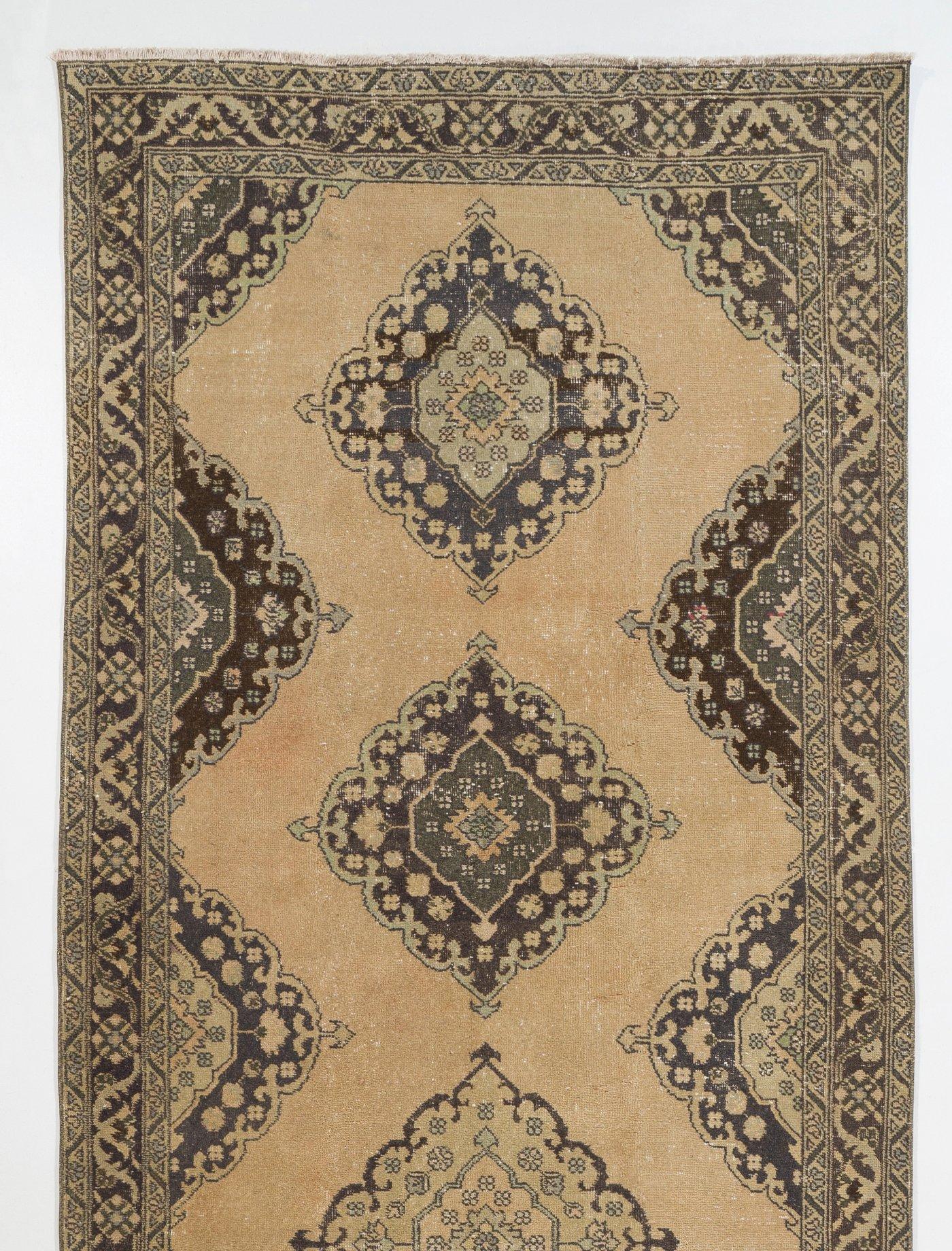 A vintage Turkish runner rug in beige, green and brown colors. It was hand-knotted in the 1960s with low wool on cotton foundation and features a multiple medallion design. It is in very good condition, professionally-washed, sturdy and suitable for