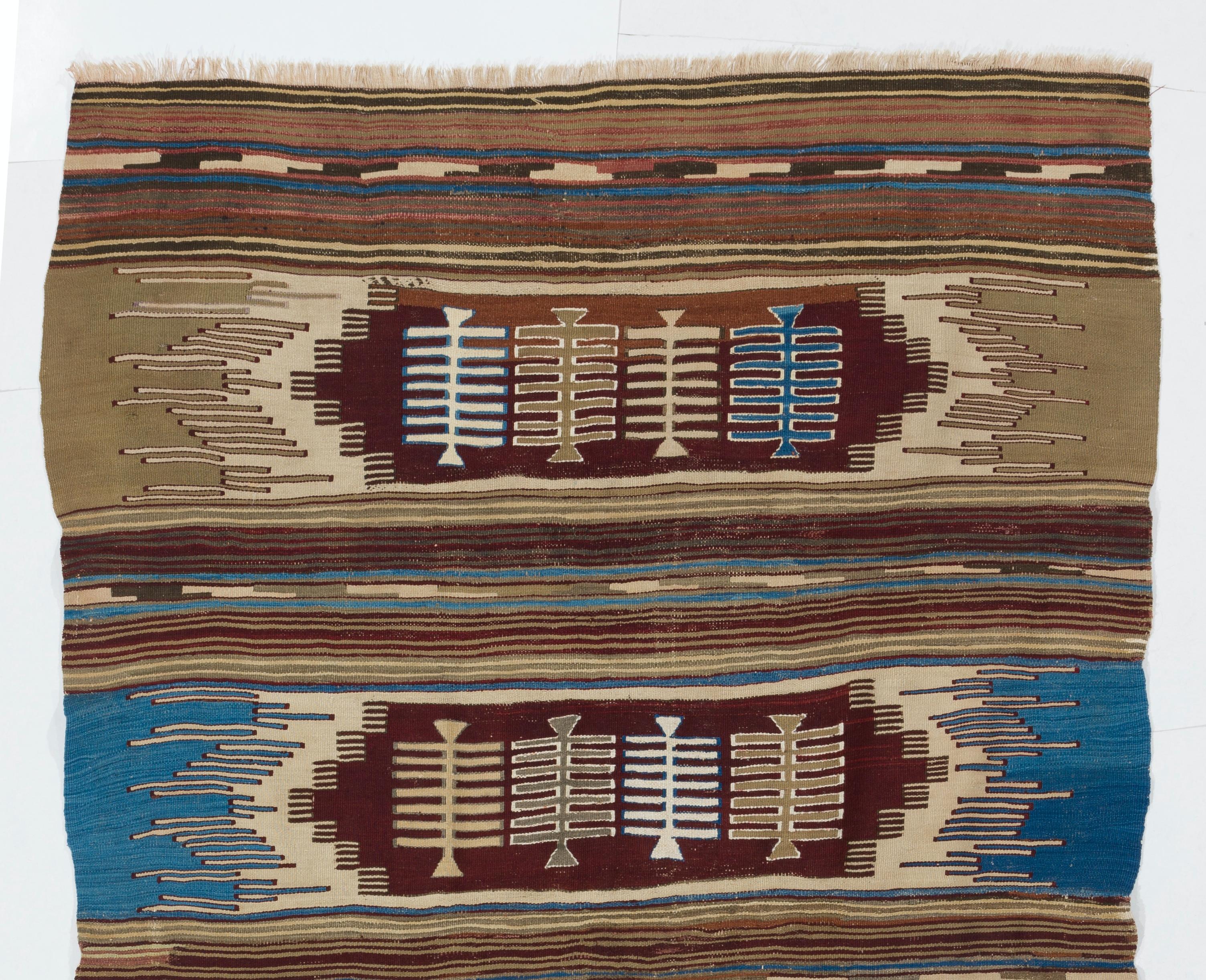 A vintage hand-woven kilim rug from Turkey, made of organic wool, featuring four comb motifs inside four elongated latch hook medallions in four rows across the width of the field in a color palette of burgundy, blue, sand beige, ivory and taupe.