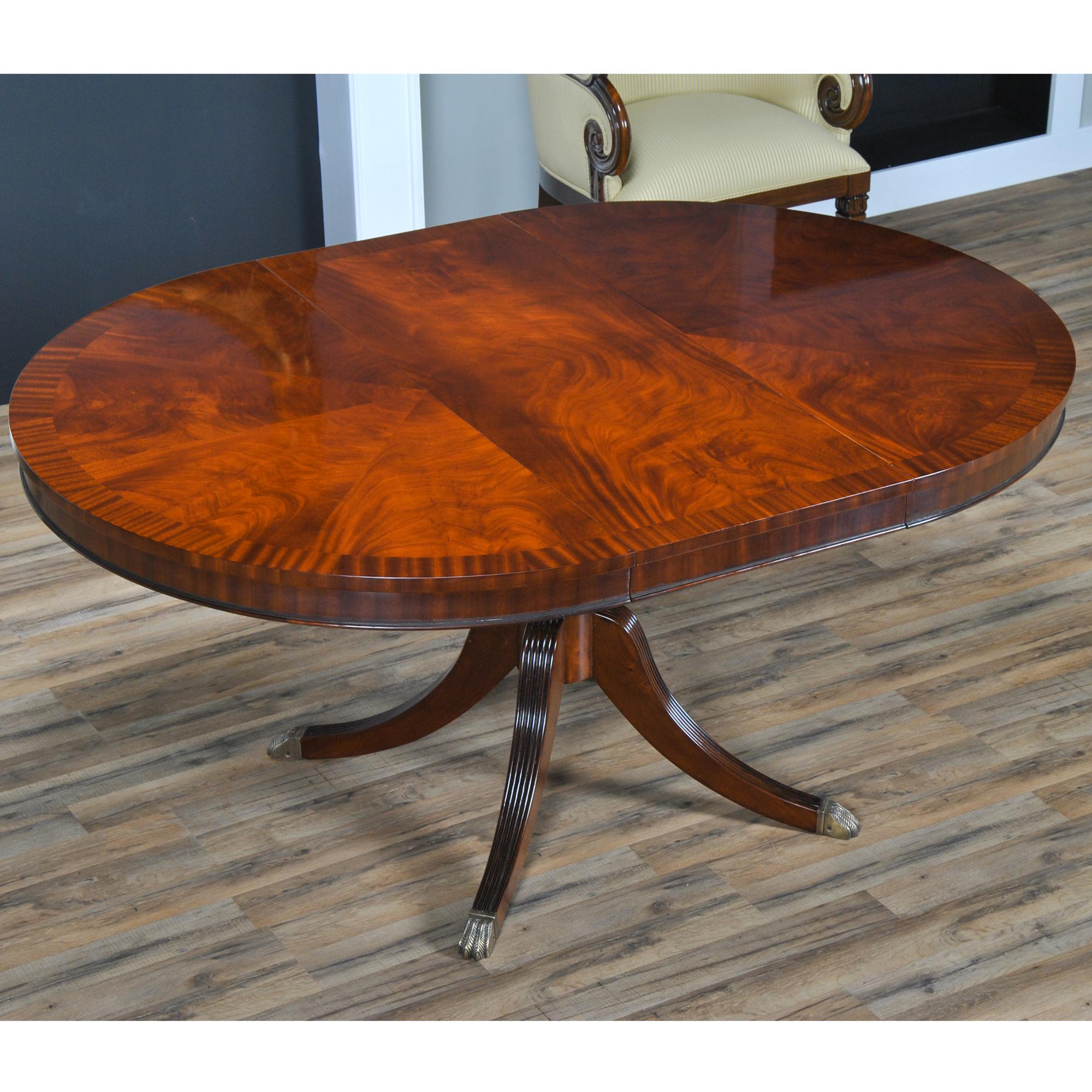 Toujours populaire, cette table à manger ronde de 48″ se transforme en une table à manger ovale de 64″ lorsque la feuille est insérée. Le plateau de la table est fixé à l'aide de boulons et repose sur une base en acajou massif cannelé. La base est