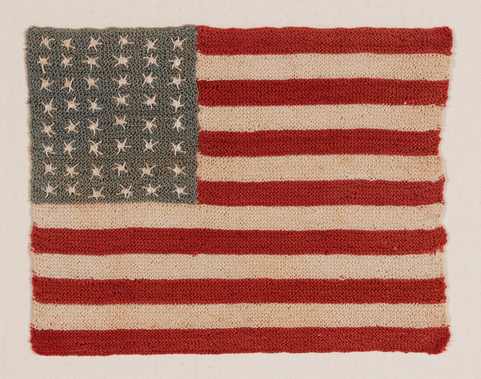 48 STARFISH-LIKE, NEEDLEWORK EXECUTED STARS ON A HAND-CROCHETED ANTIQUE AMERICAN FLAG FROM THE EARLIEST PART OF THE 48 STAR ERA, 1912-WWI (U.S. INVOLVEMENT 1917-18) OR EVEN PRIOR TO THE RESPECTIOVCE STATES’ ADDITION; AN EXCEPTIONAL LITTLE EXAMPLE OF