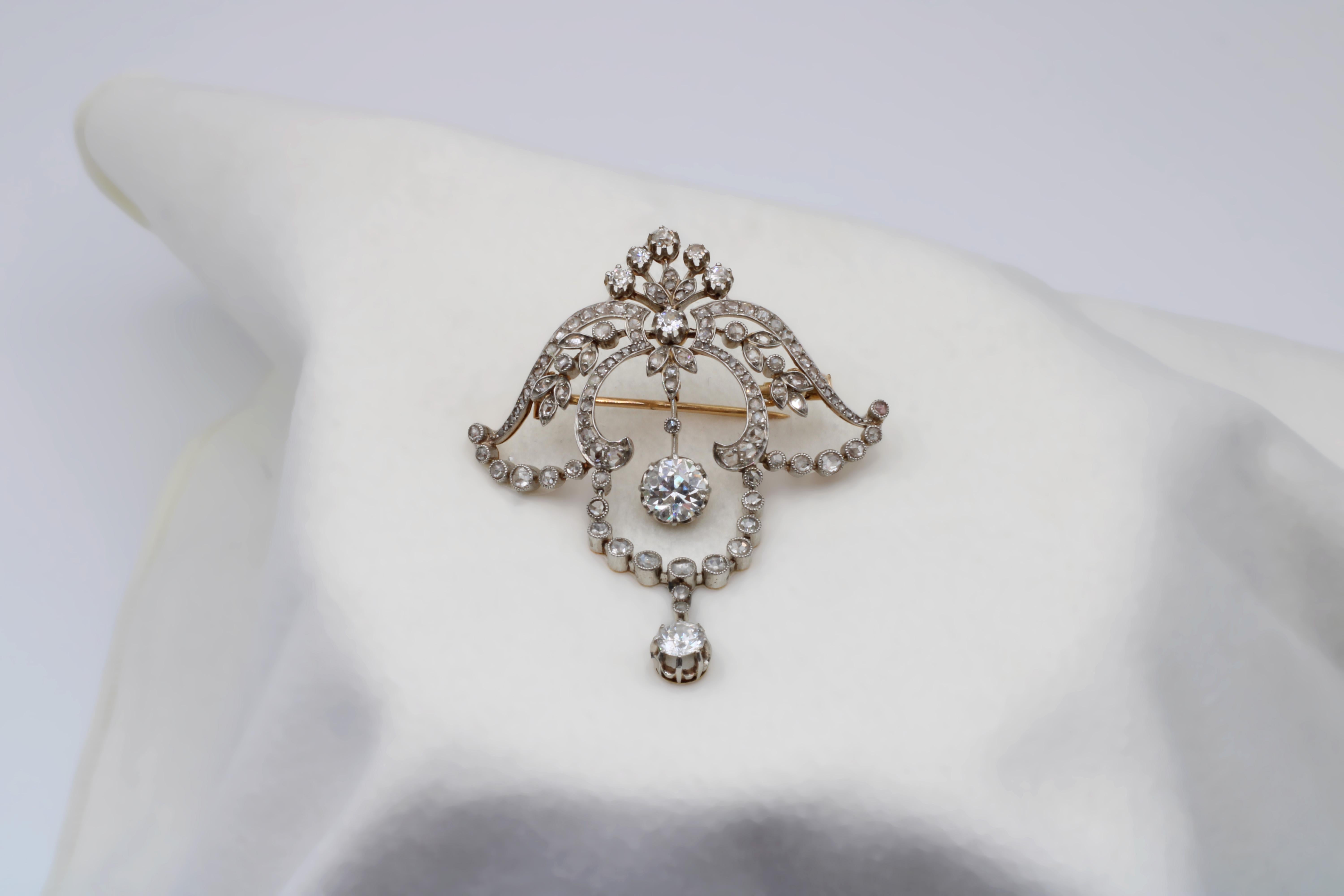 A classic Victorian drop-brooch featuring centerpieces of Old European diamonds enveloped by concaving and curving rose-cuts patterns, especially floral patterns that burst all across the piece and amplify its beauty. In great condition despite its