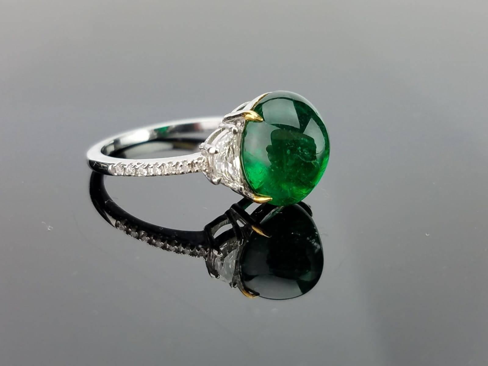 A classic three stone ring, with a 4.80 carat lustrous and deep coloured Zambian Emerald cabochon centre stone and 2 half-moon side stone diamonds. Currently a ring size US 6, but we can resize the ring for you without additional cost. Can be