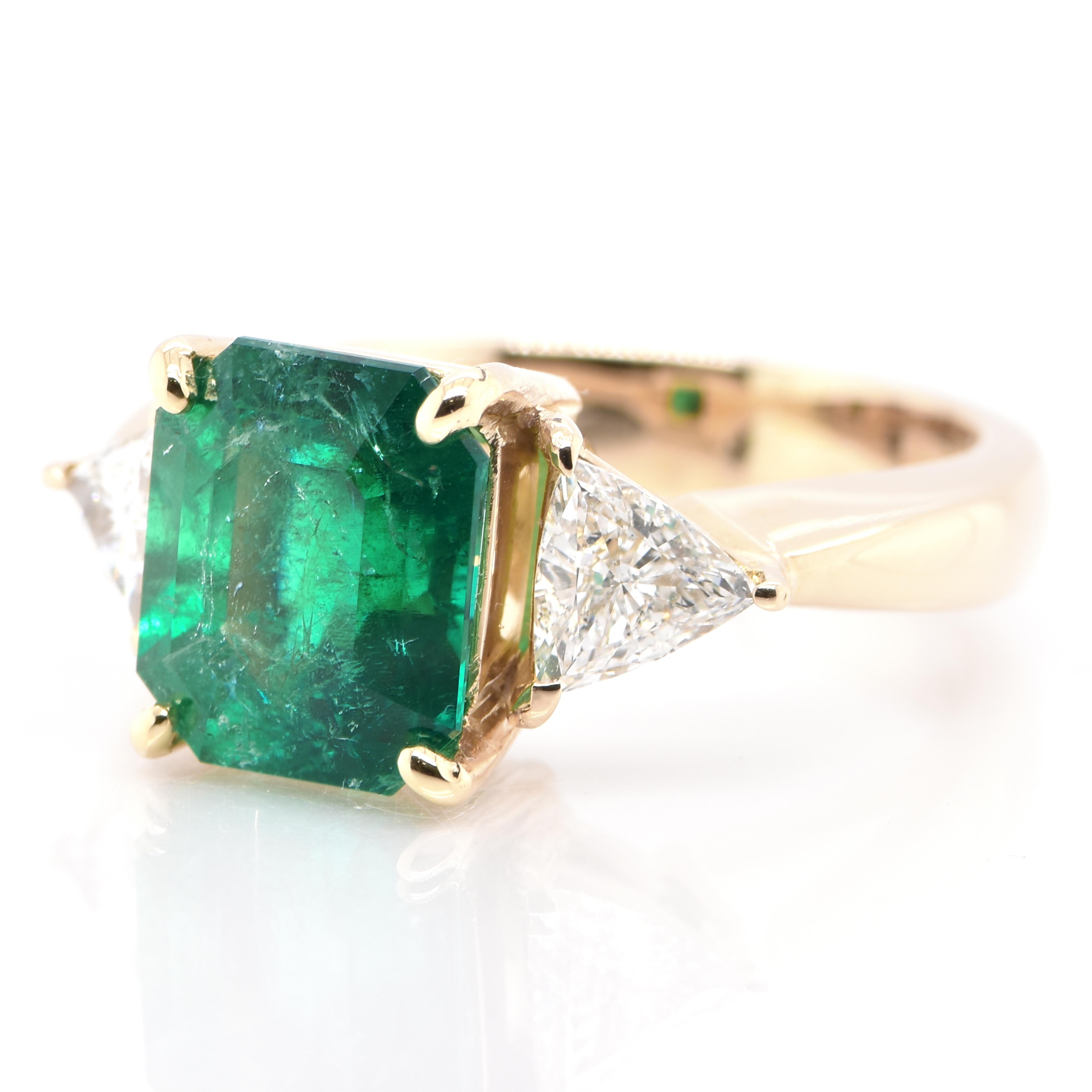 A stunning Three-Stone Ring featuring a 4.80 Carat, Natural, Colombian Emerald and 0.64 Carats of Diamond Accents set in 18K Yellow Gold. People have admired emerald’s green for thousands of years. Emeralds have always been associated with the