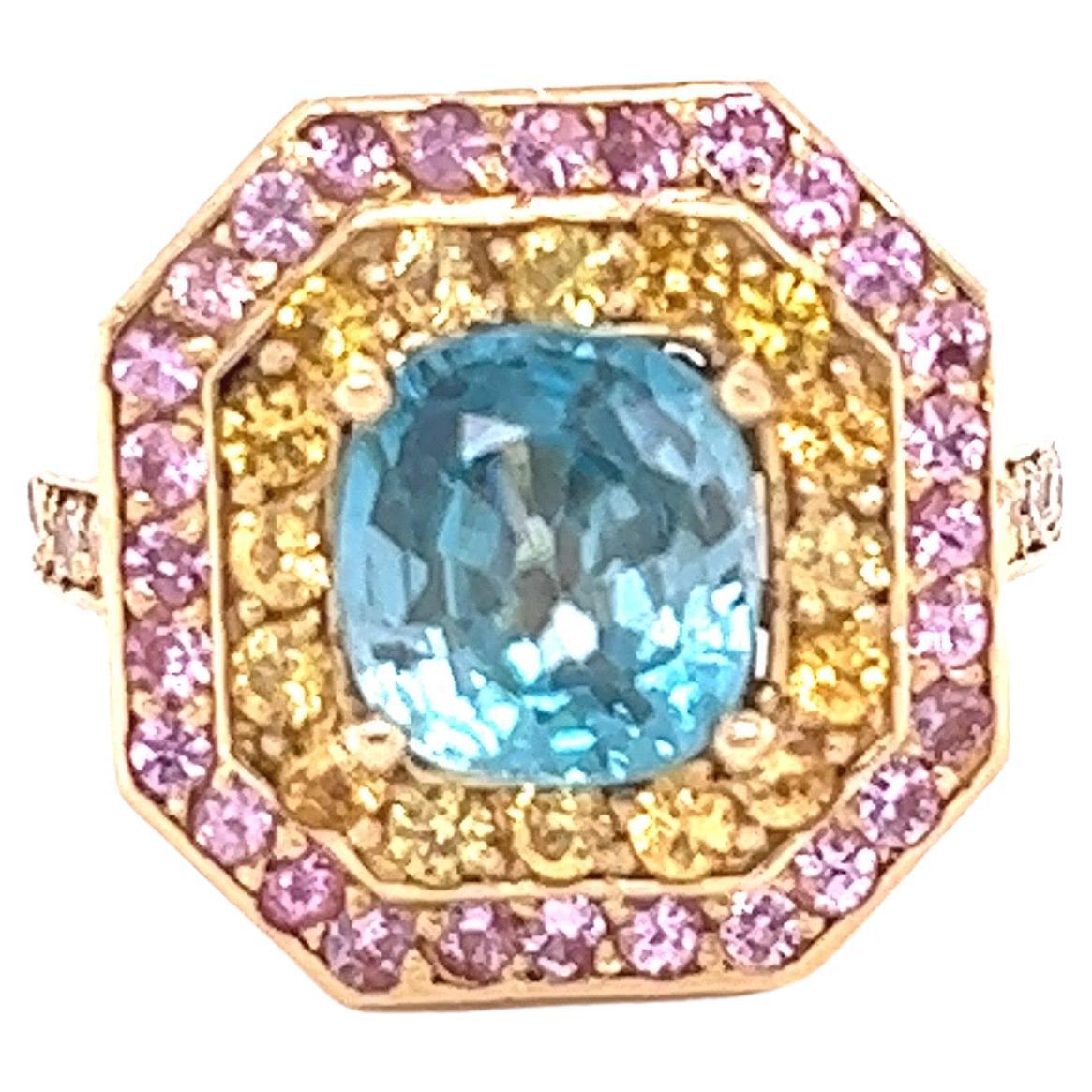 Blue Zircon is a natural stone mined mainly in Sri Lanka, Myanmar, and Australia.  
This ring has a beautiful Natural Cushion Cut Blue Zircon that weighs 3.31 carats and is surrounded by 28 Natural Pink Sapphires that weigh 0.61 Carats and 16