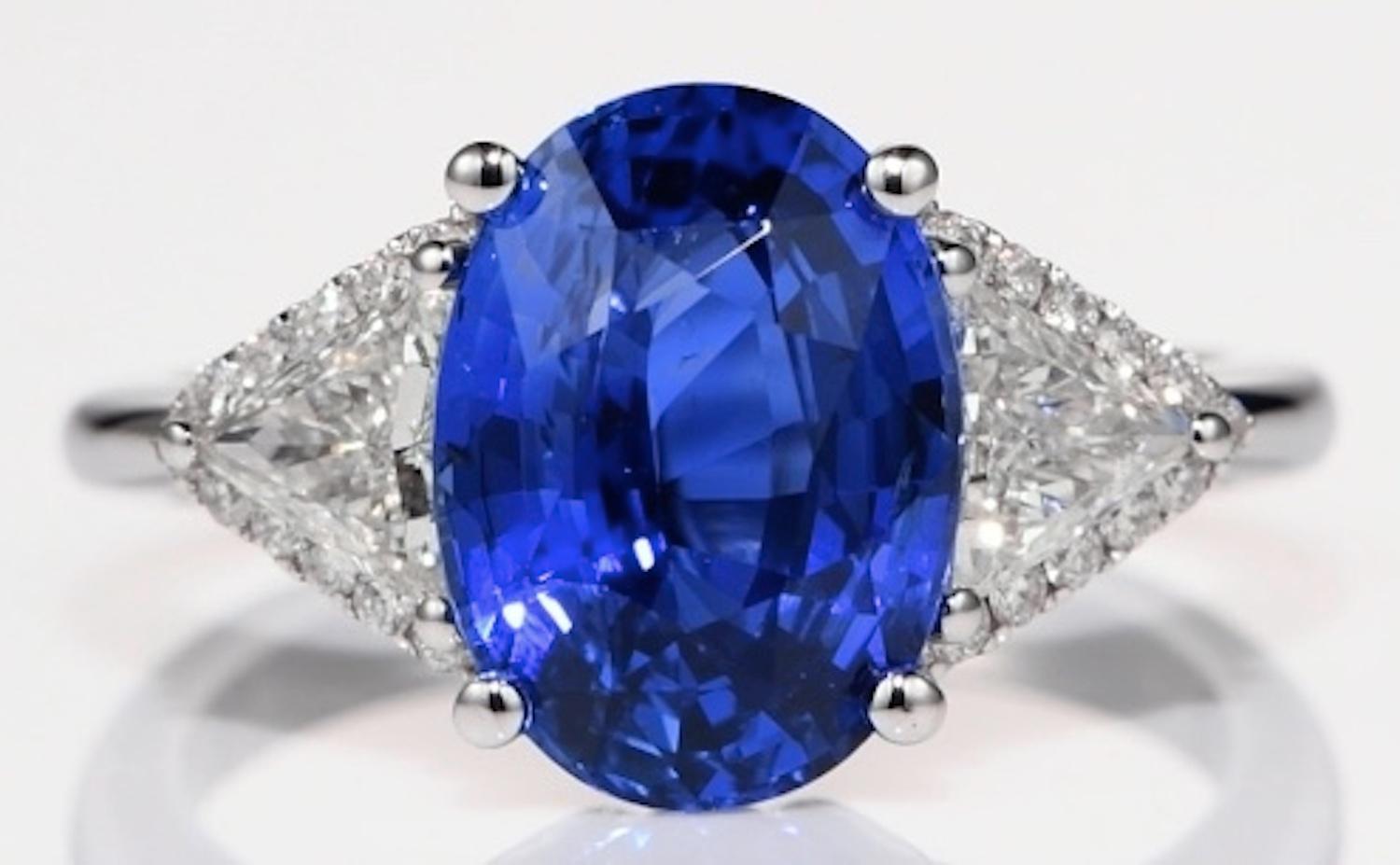 This beautiful, elegant and timeless ring is set with an incredible oval-cut Ceylon blue sapphire, weighing 4.81 carats, flanked on either side by two diamonds weighing 0.61 carats (combined), framed by 22 sparkling diamonds totaling 0.15 carats and