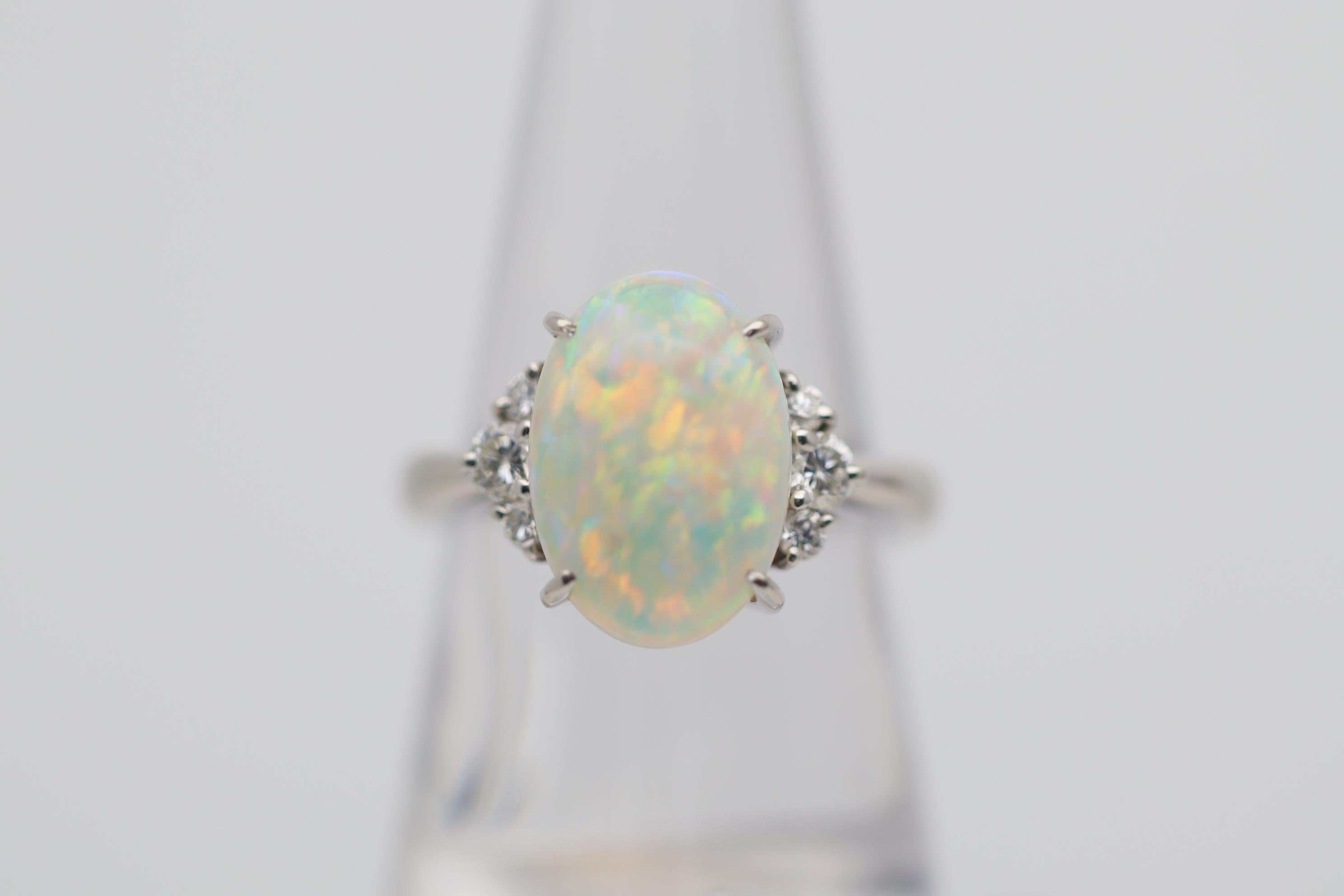 A simply stunning gorgeous Australian crystal opal takes center stage of this platinum made ring. The opal weighs 4.83 carats and has some of the best play-of-color we have seen in years! The primary colors are red and orange with some blues,