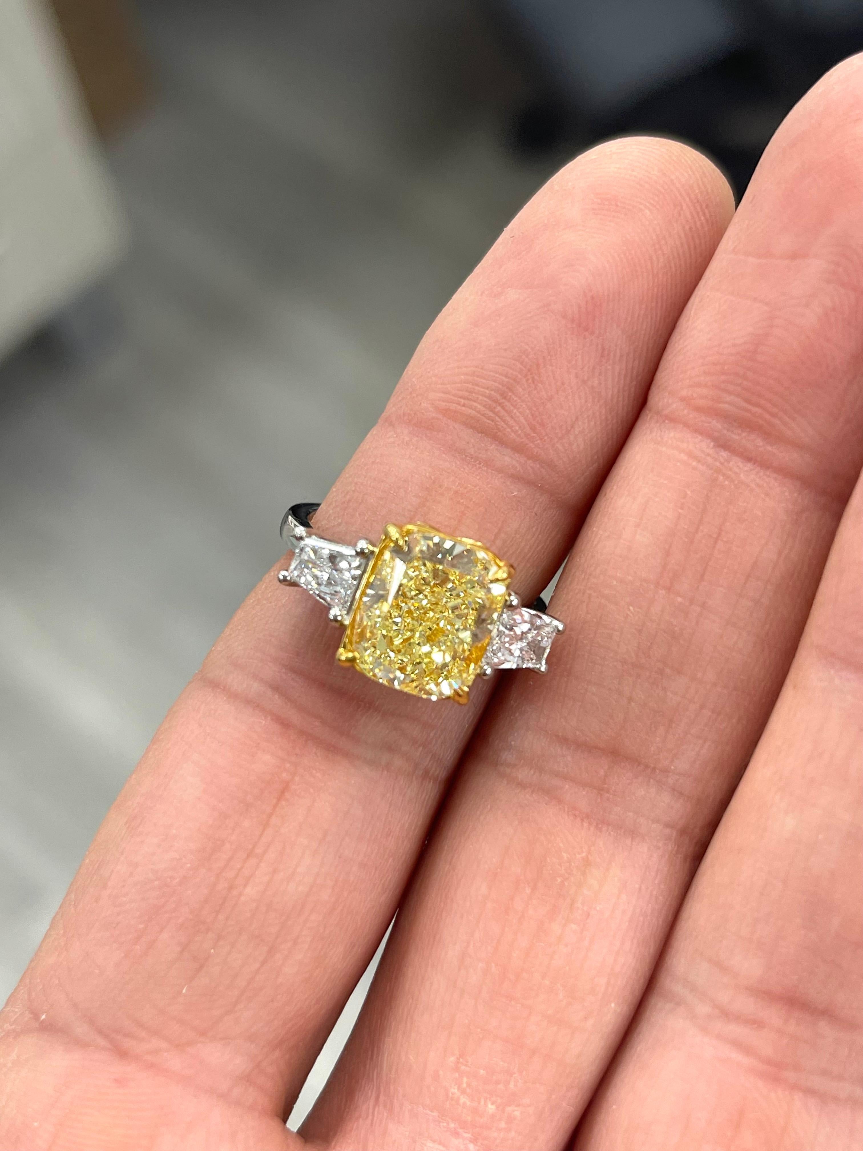 Fancy Yellow Cushion just under 5 carats in a unique three stone ring with elongated trapezoids, almost the look of tapered baguettes 
Plat and 18kt Yellow Gold with 0.71ct Trapezoids
Strong Fancy Yellow color
This piece can be viewed before