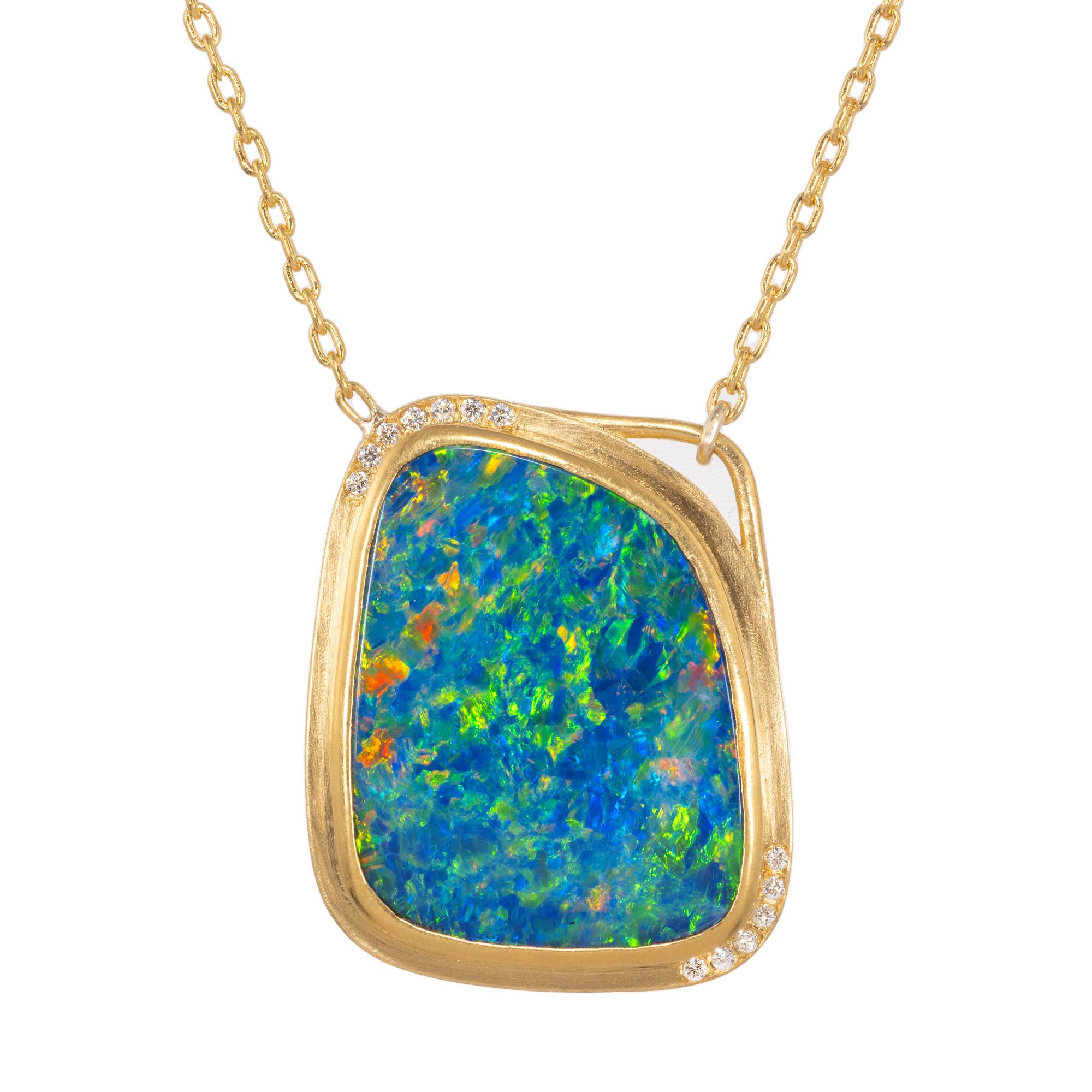 Australian boulder opal of strong blue and green color, accented with red flashes. 4.85ct freeform opal mounted in a handmade 22k yellow gold bezel and frame and accented with 13 full cut round diamonds. diamond accents. The boulder opal, with its