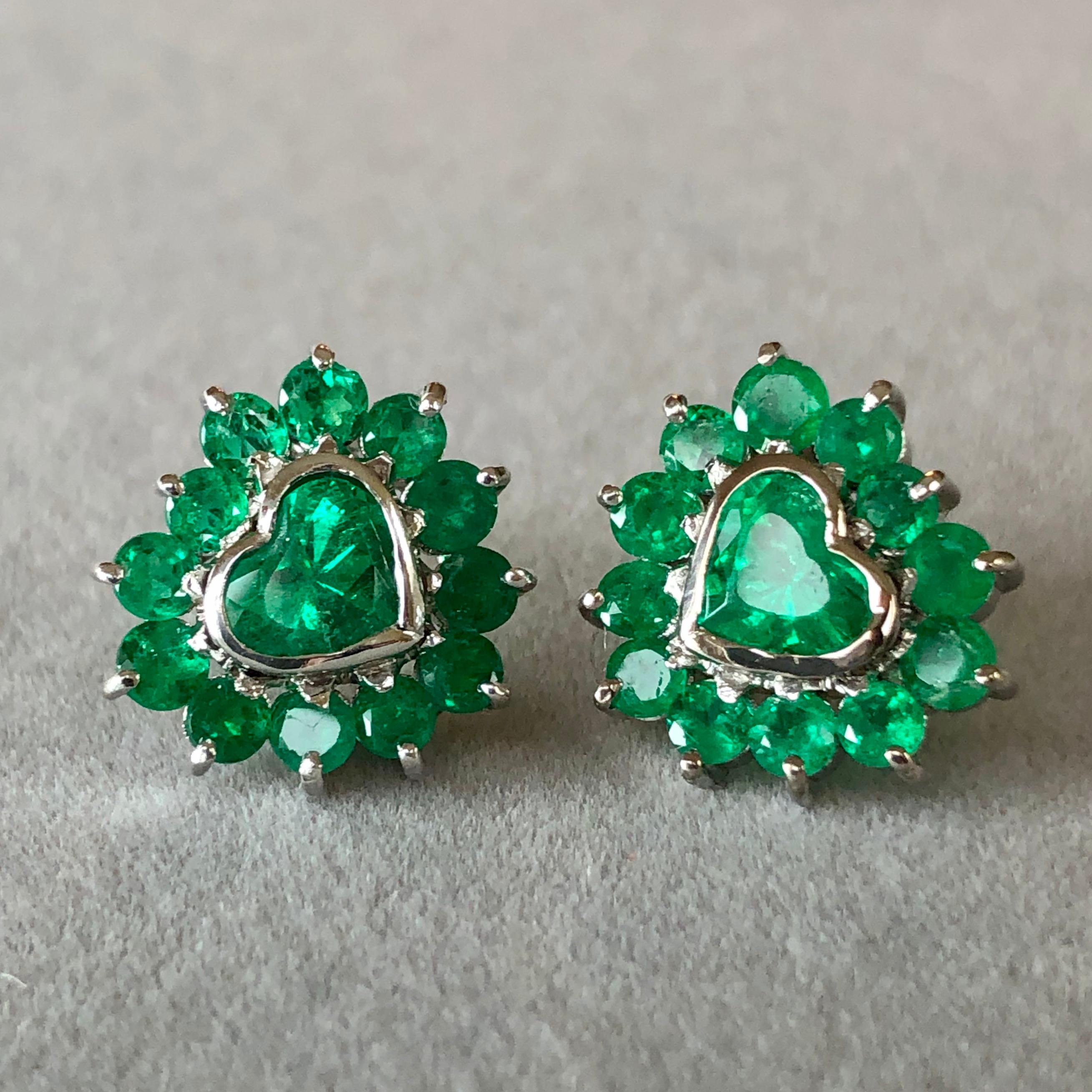 18k earrings with 2 heart shape Colombian emeralds weighing 2.00 carats and 26 round Colombian emeralds weighing 2.85 carats. The beauty of heart shapes- perfectly matched Colombian emeralds are exquisitely handcrafted 18K white gold mountings.