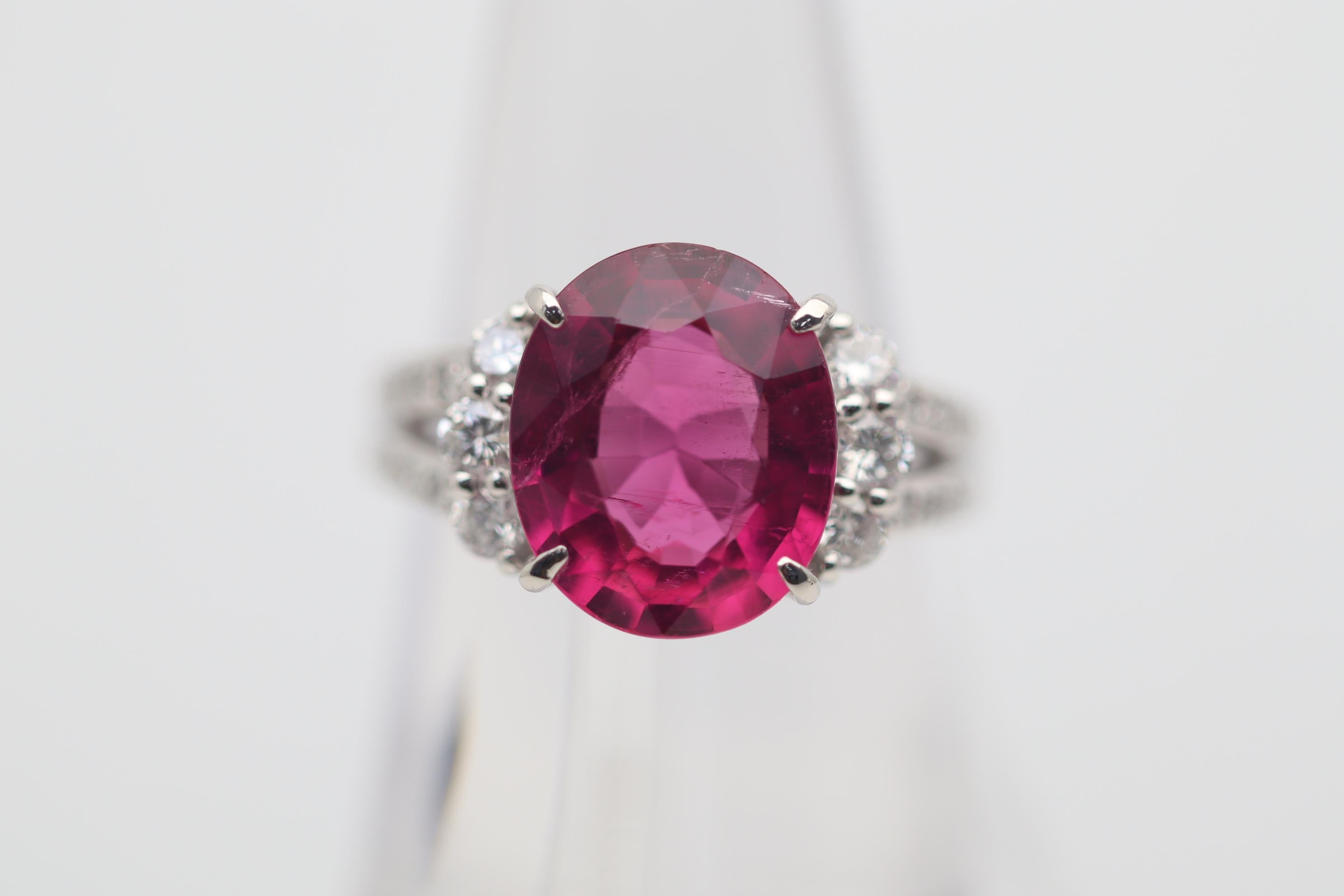 A superb top gem-quality rubellite tourmaline takes center stage. It weighs 4.85 carats and has a bright electric vivid pink-red color. The brilliance and light return of the tourmaline is very impressive which is due to the stone’s natural clarity