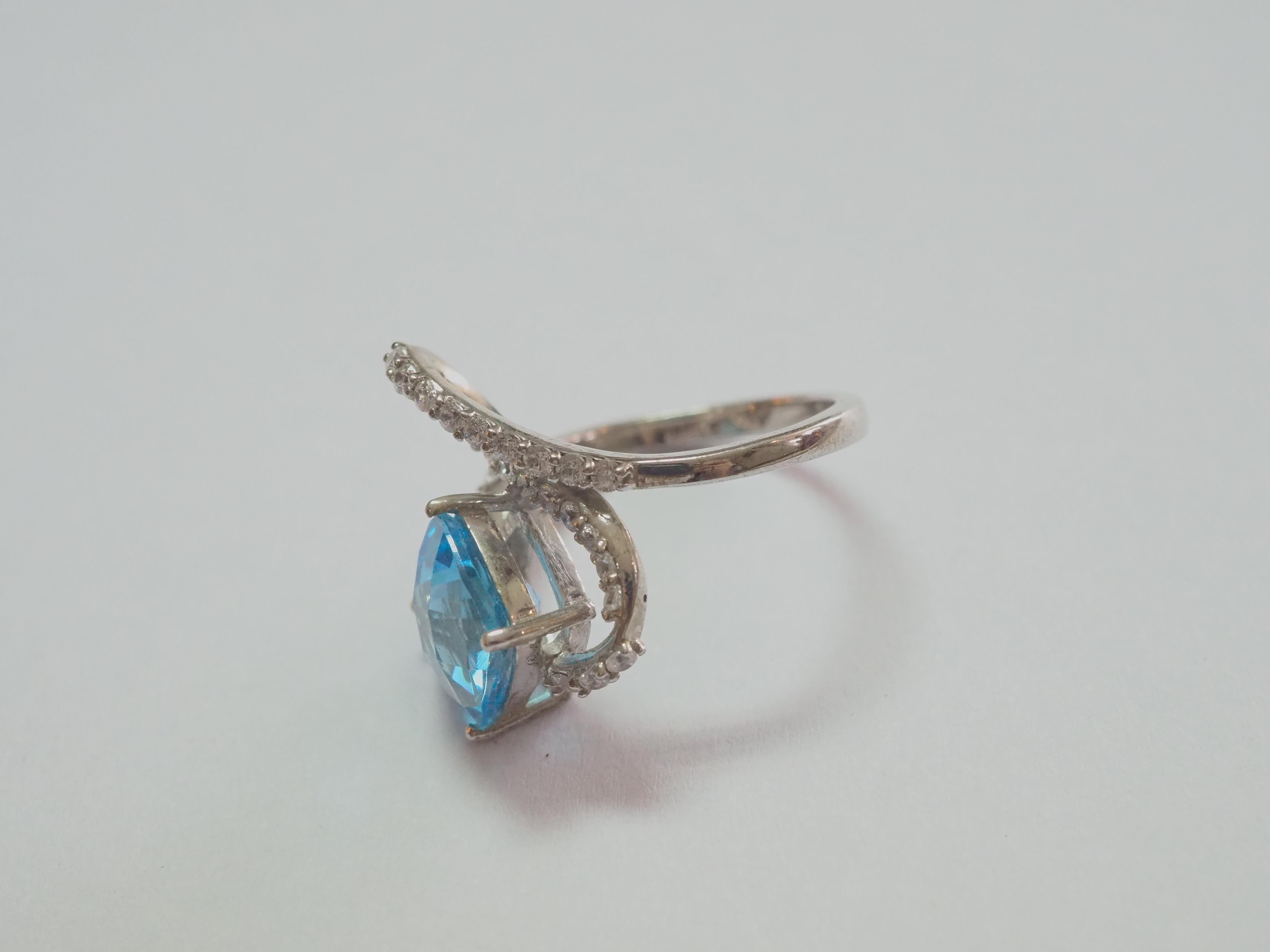 Starting at only 50!

This ring is a stunning wavy fashion ring in solid sterling silver. The ring is decorated by natural cushion blue topaz prong set as the main stone. The surrounding white stones on the band are cubic zirconia. The unique design