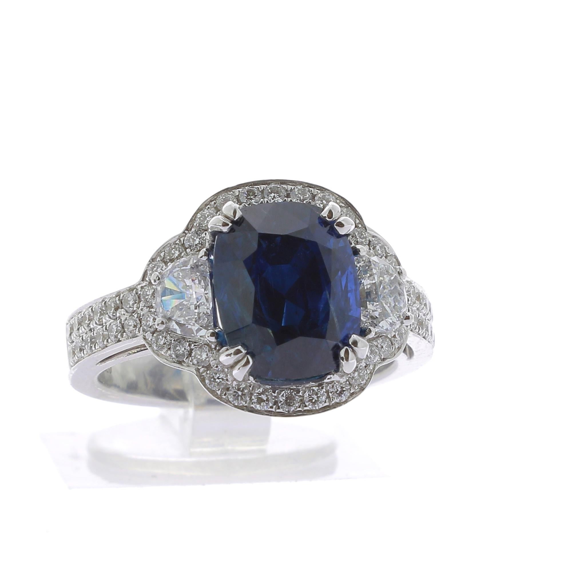 An extraordinary Burmese Sapphire Ring.
This cushion Burma Sapphire shape is weighing 4.86 Carats.
The color of the Myanmar Sapphire is an intense blue.
The ring is set with two half-moon diamonds weighing 0.58 Carats and surrounded by 54 round