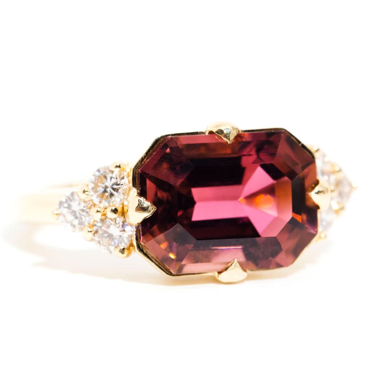 Forged in 18 carat yellow gold, this uniquely designed art deco inspired ring features an alluring 4.87 carat bright reddish pink emerald cut Tourmaline complimented by glittering round brilliant cut diamonds. We have named this stunning ring The