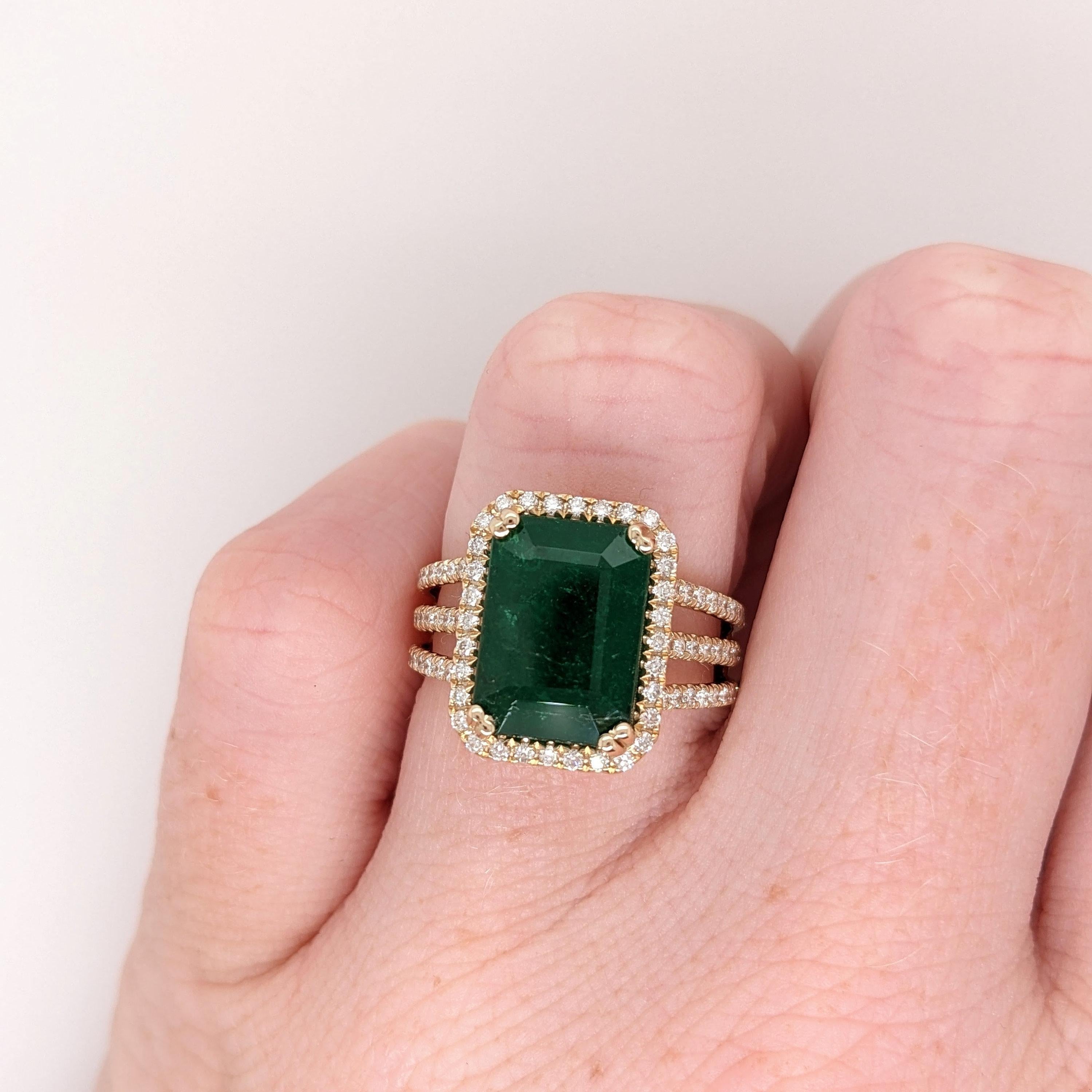 A gorgeous ring featuring a beautiful deep green emerald set in solid 14k yellow gold with all natural diamond accents. Enjoy a little extra sparkle with the diamond studded layered split shank! A gorgeous modern look for an elegant addition to any