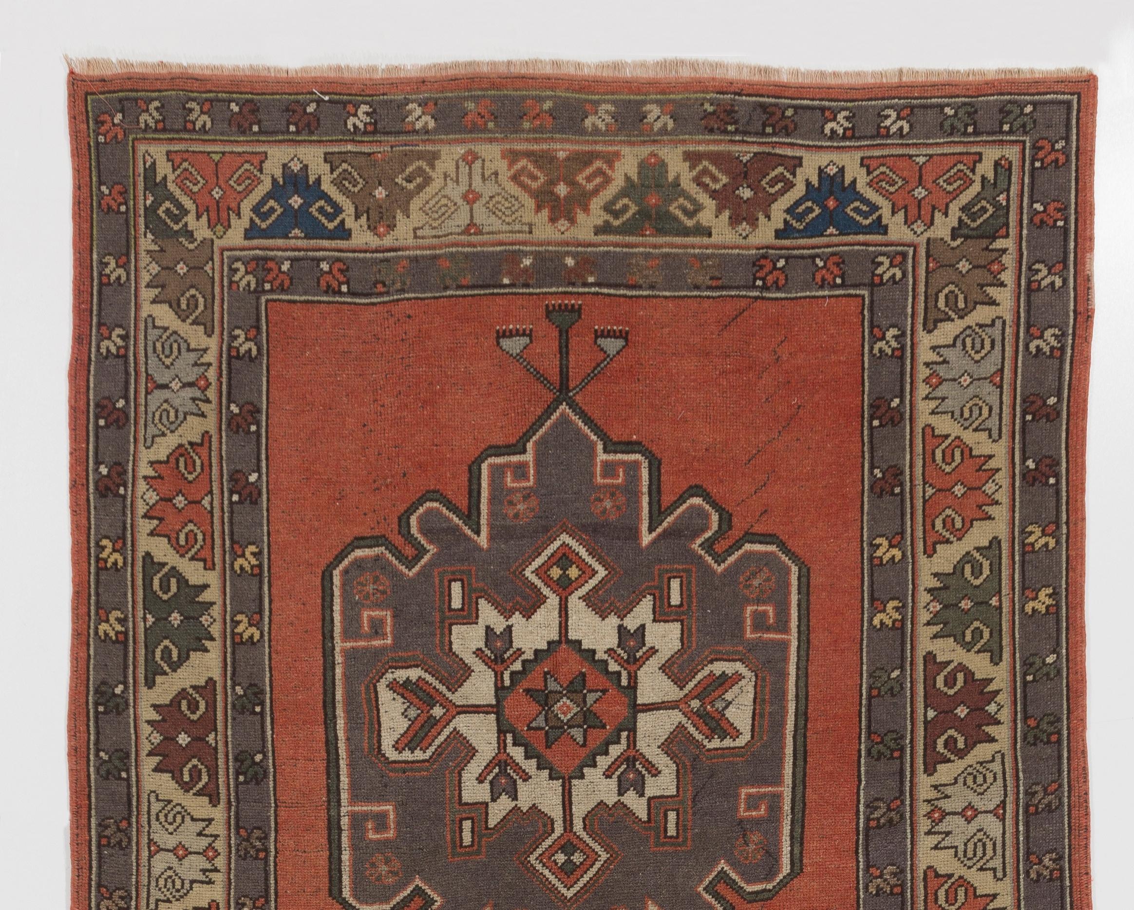 This is a vintage hand knotted Turkish runner featuring three linked medallions in gray against a plain field in warm burnt orange/terra-cotta. The guard strips and the main border take up a large space and are decorated with abstract floral motifs