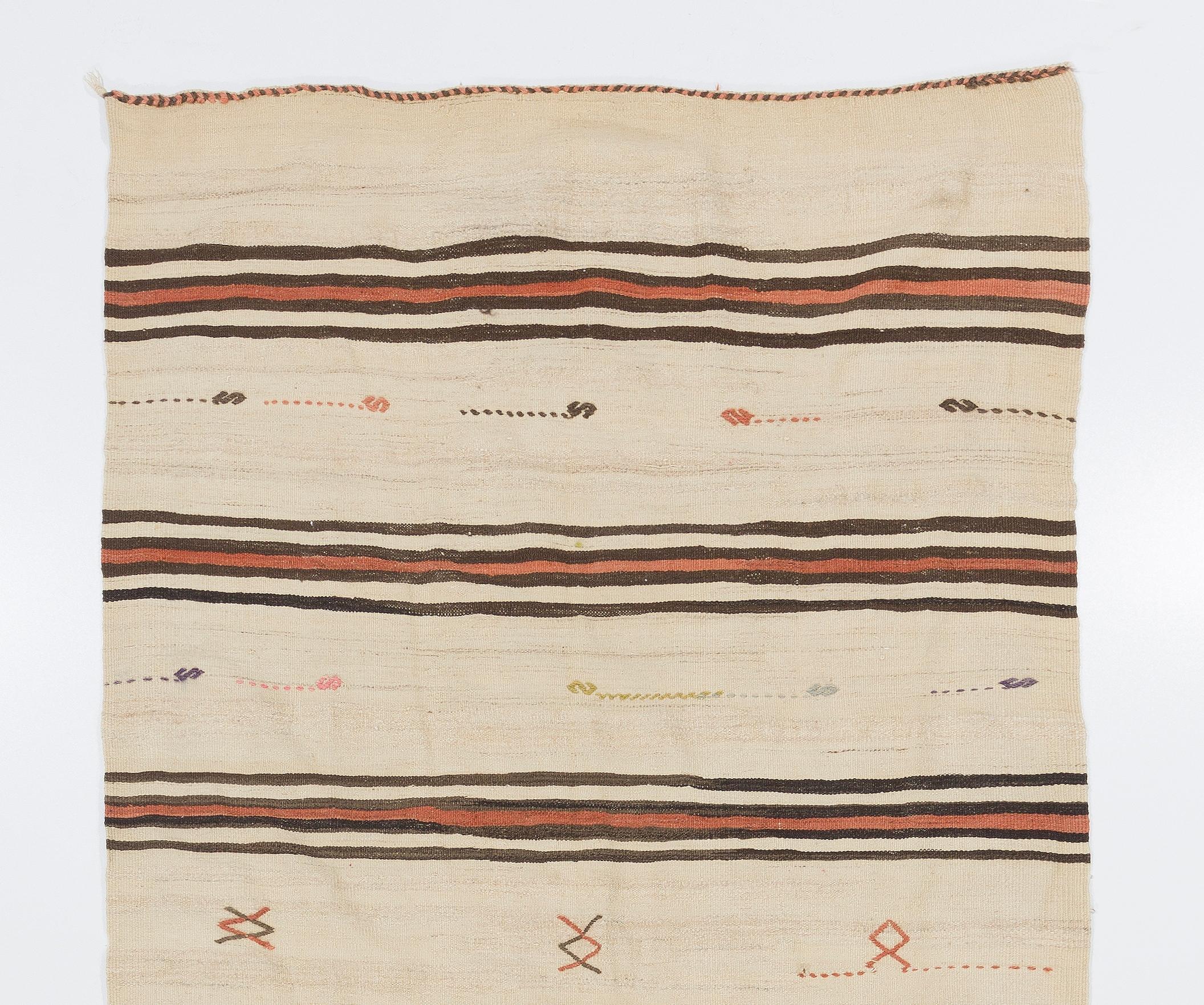 A simple yet beautiful wool flat-weave rug handwoven by the nomadic tribes in South Central Turkey that has a design of stripes in beige, brown and madder red and minuscule simple geometric motifs such as hooks and diamonds in various other colors