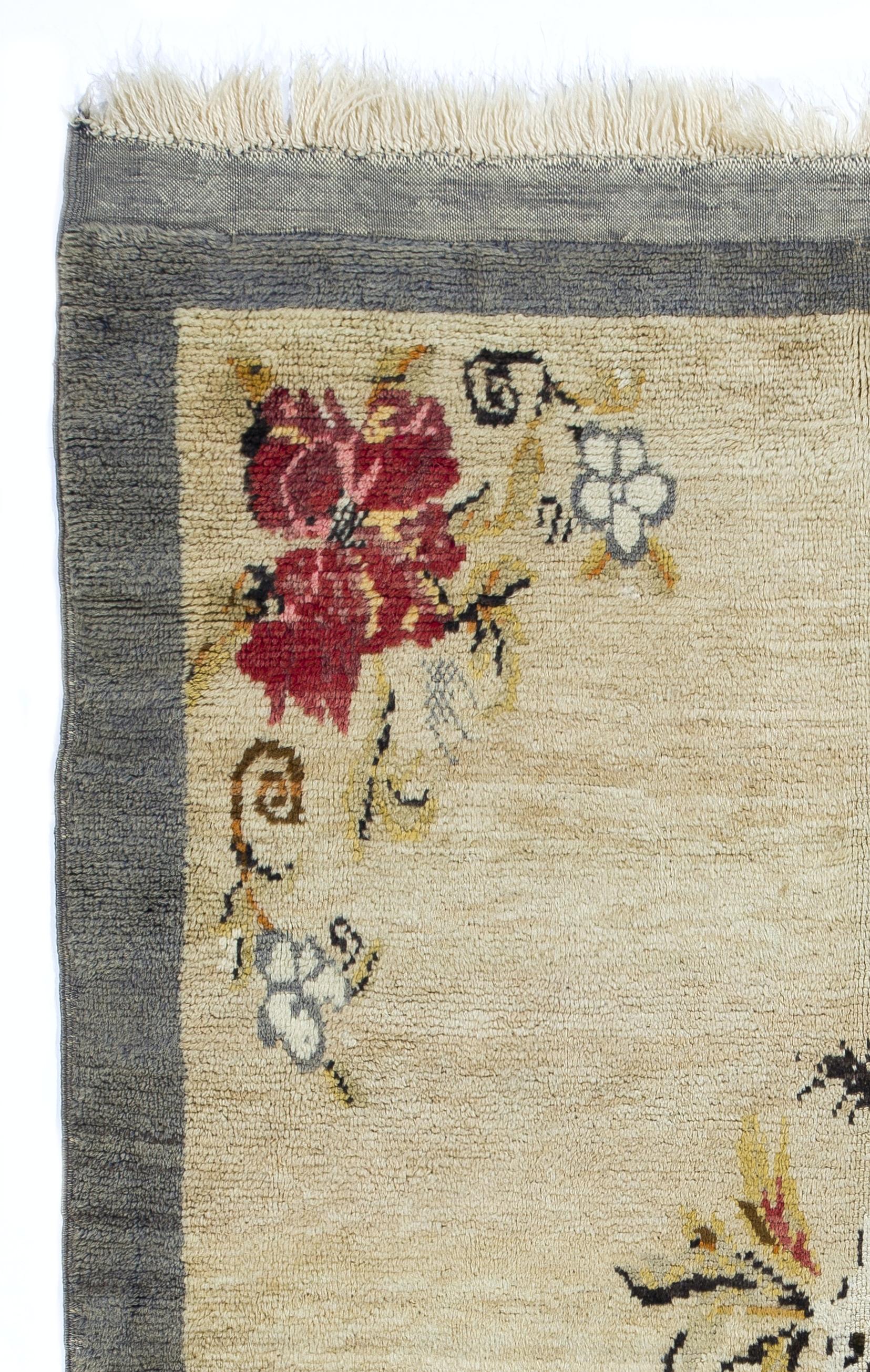 A vintage hand-knotted rug from Central Turkey, made of velvety lamb's wool, featuring large floral motifs in red, white, gray and tawny brown at its center and corners, against a plain, ivory background and a solid border in gray.

The rug was