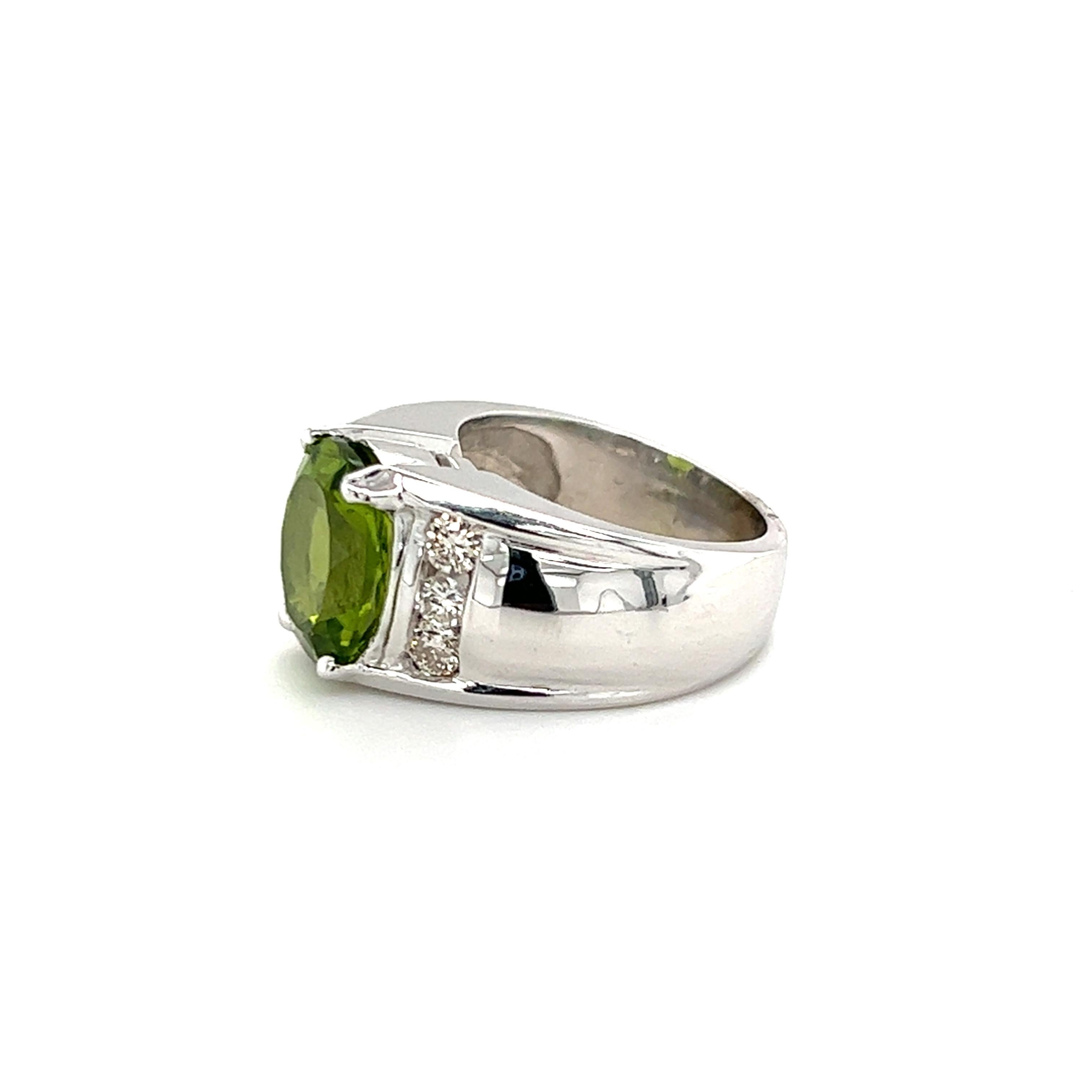 One 14-karat white gold ring set with one center oval peridot stone, approximately 4.90 carat total.  The center stone is flanked by six (6) channel set round brilliant cut diamonds, approximately 0.63-carat total weight with matching H/I color and