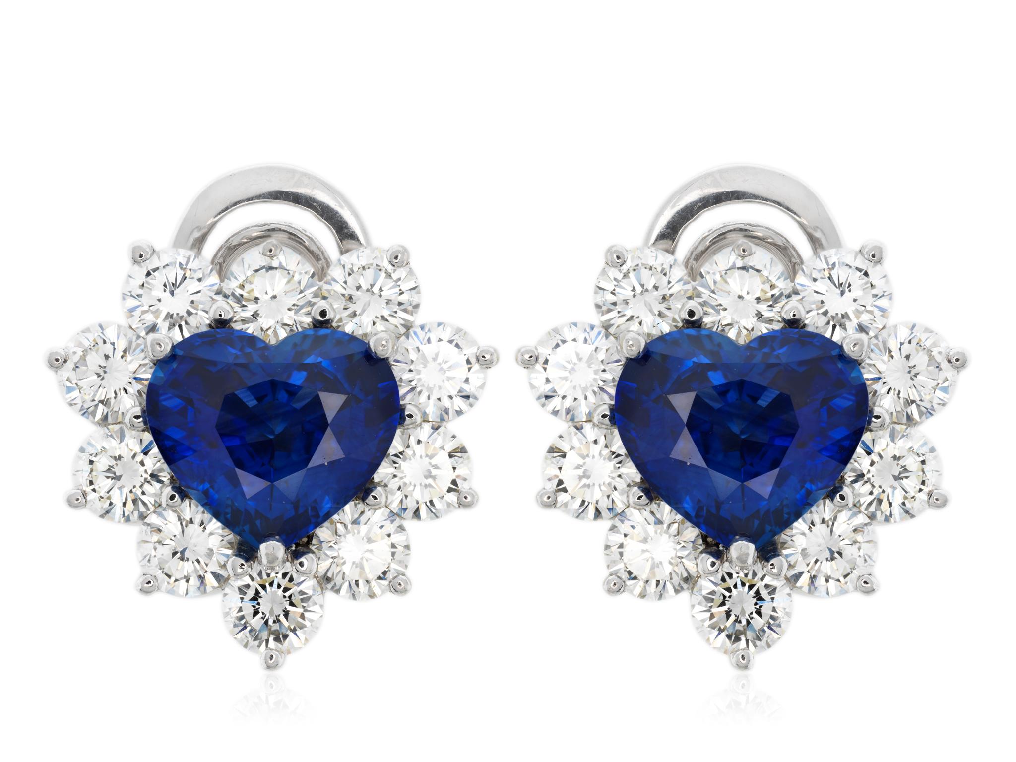 Platinum heart shaped sapphire and diamond earrings featuring two heart shaped sapphires with a total weight of 4.91 carats, framed with a halo of ten round brilliant cut diamonds with a total weight of 3.66 carats with a color and clarity of G VS2