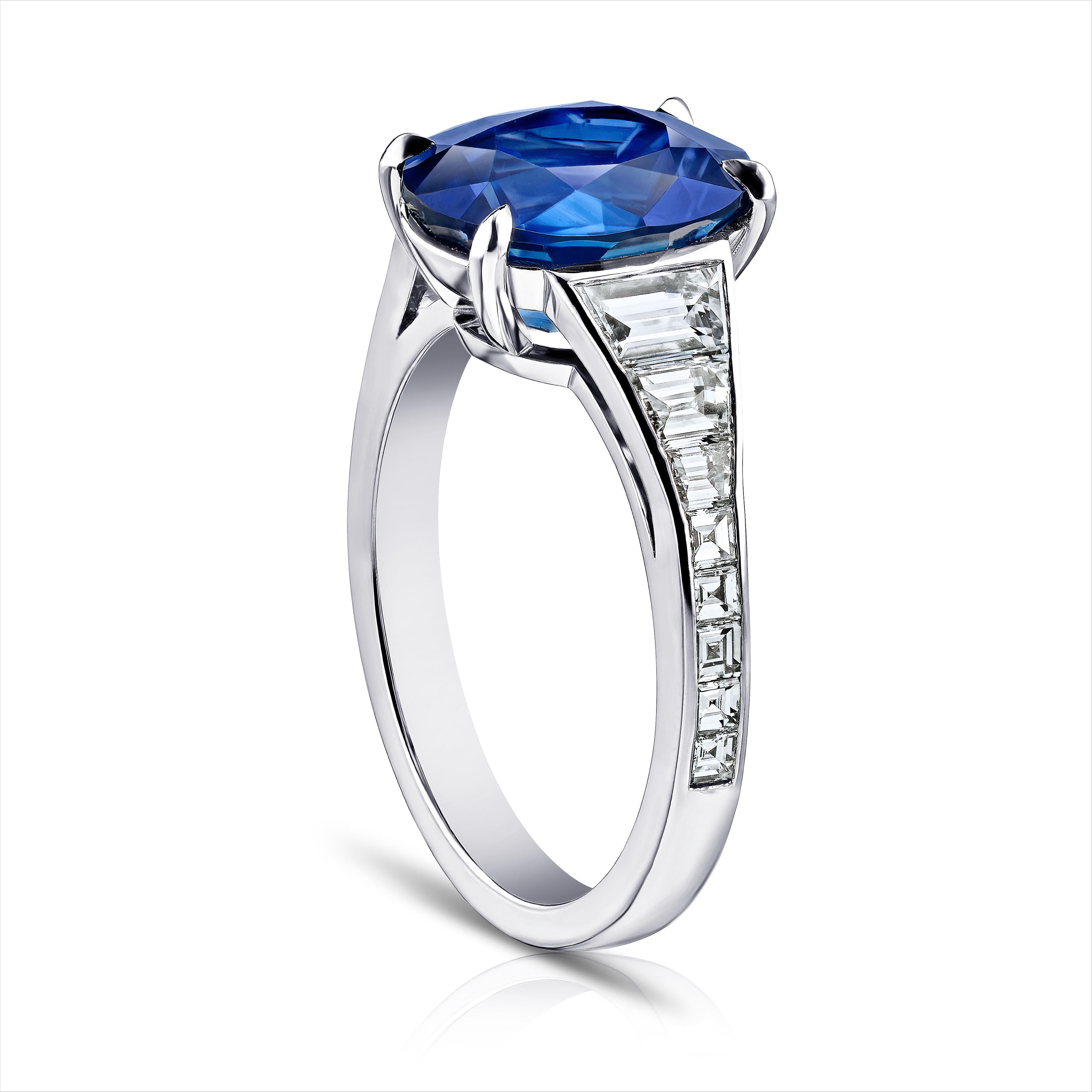 4.91 carat oval blue sapphire with six trapezoid step cut diamonds .83 carats and 10 carre diamonds .30 carats set in a platinum ring.