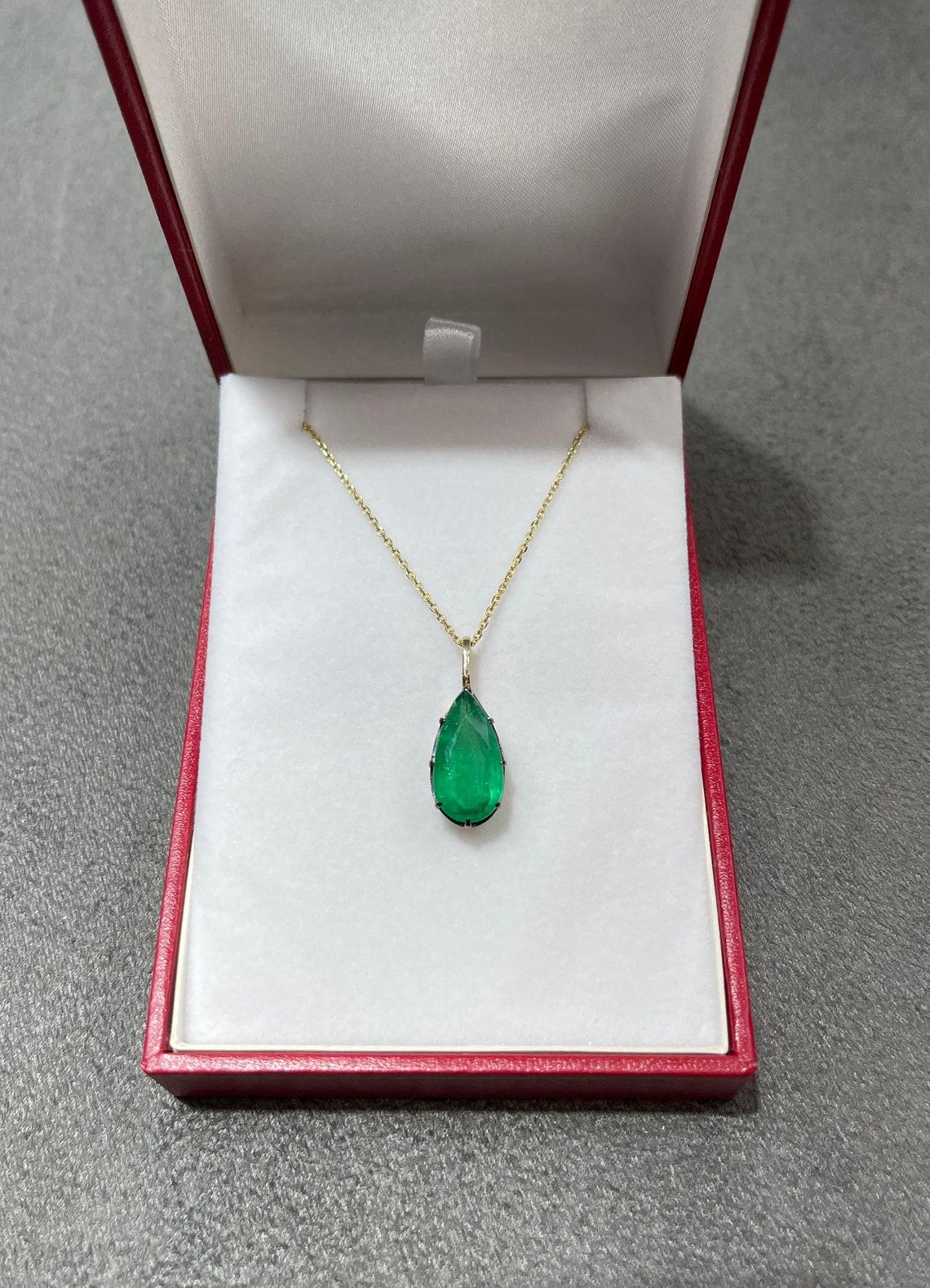 Displayed is a natural emerald Georgian styled solitaire pendant in 14K yellow gold. This gorgeous solitaire pendant carries a full 4.91-carat emerald in a prong setting. Black rhodium highlights the emeralds' bezel and prongs. Fully faceted, this