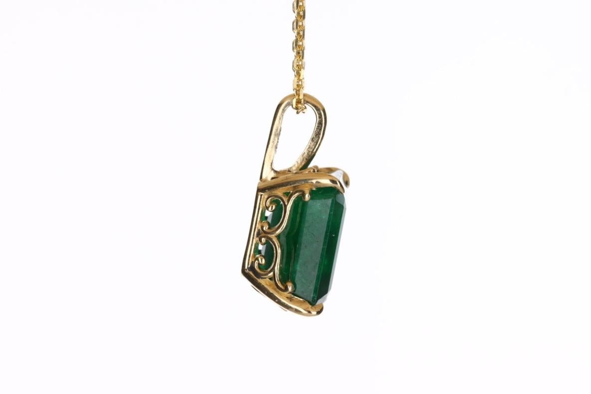 Displayed is a classic Colombian emerald solitaire necklace set in 14K yellow gold. This gorgeous solitaire pendant carries a large 4.92-carat emerald in a four-prong setting. The gem has a dark green color and very good luster. An ideal solitaire,