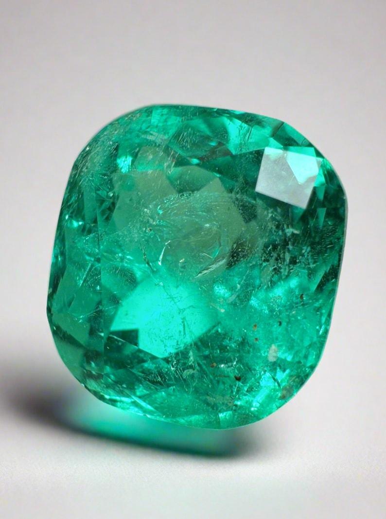 Stone: Emerald
Weight: 4.93-carats
Shape: Cushion Cut
Clarity: Transparent
Luster: Excellent
Color: Vivid Bluish Green
Measurements: 10.37mm x 9.57mm x 7.85mm
Geographic Origin: Colombia
Treatment: Natural, Minor Oil

Comments: Due to their growth