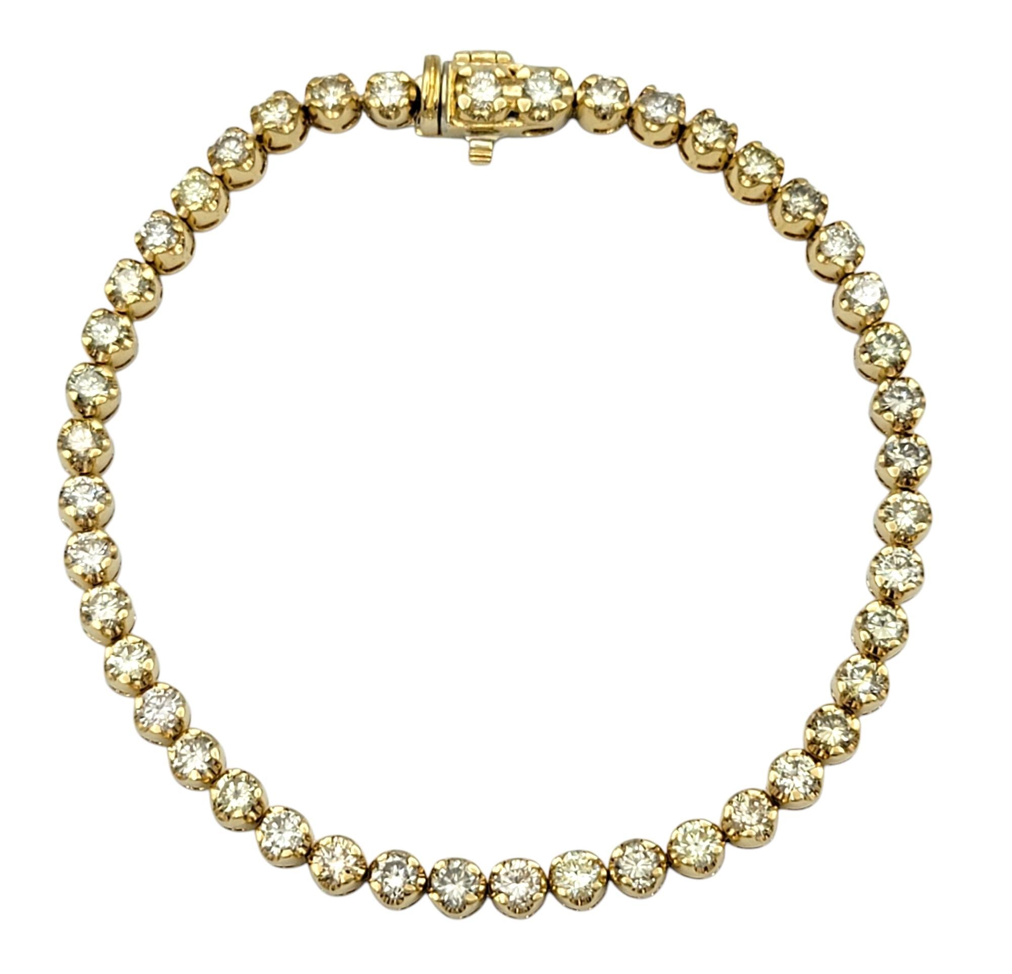 Timeless elegance meets radiant sparkle in this classic diamond line bracelet. Crafted in luxurious 18 karat yellow gold, the bracelet features a seamless row of forty-four round brilliant cut diamonds, creating a fluid line of brilliance across the