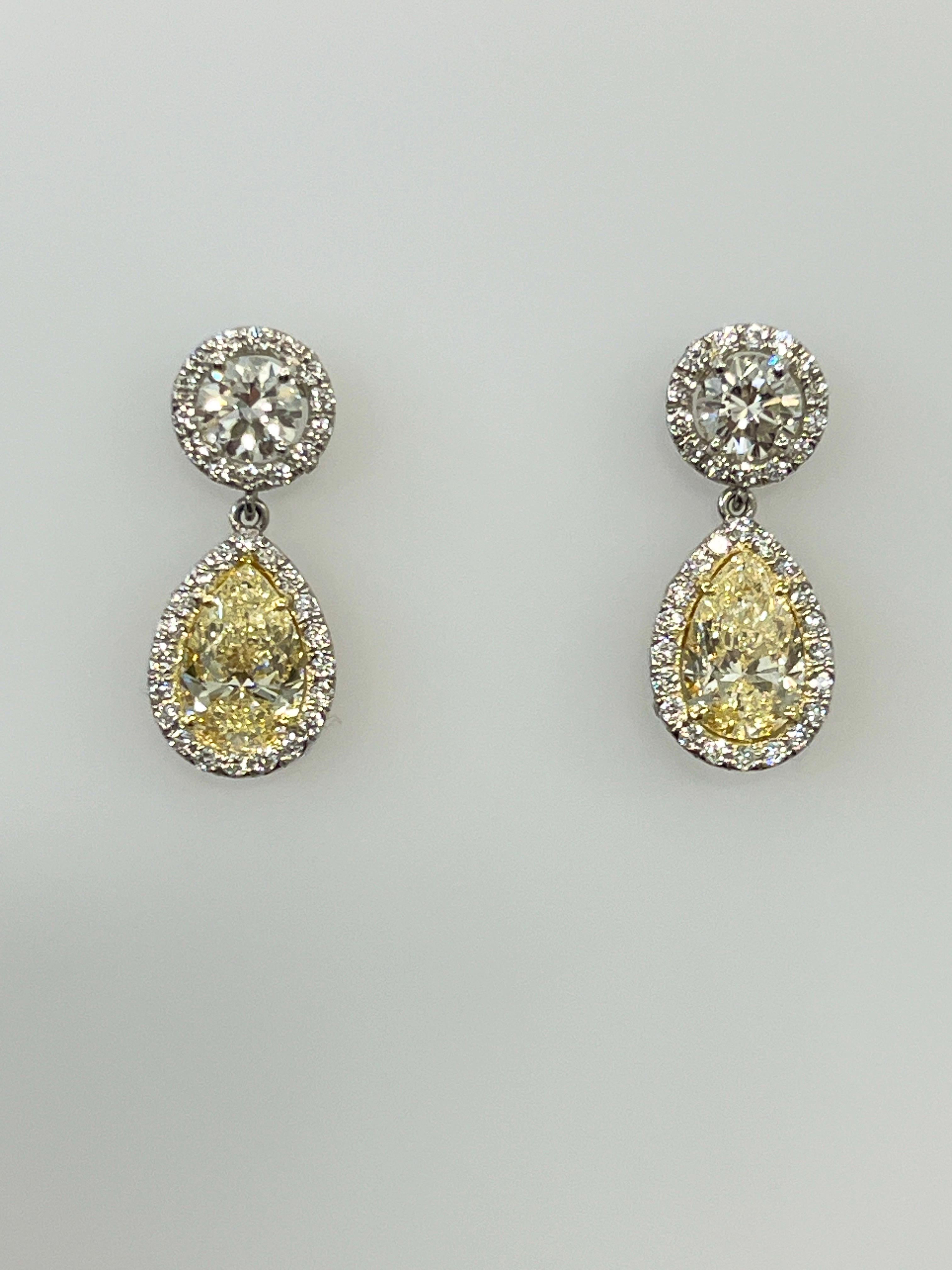 These stunning 4.93 ct natural yellow and diamond dangle earrings are sure to make heads turn. With a VS1 in clarity, the surrounding diamonds around the stone are a G/H in color and VS2/SI1 in clarity. They are a must have for any wardrobe.