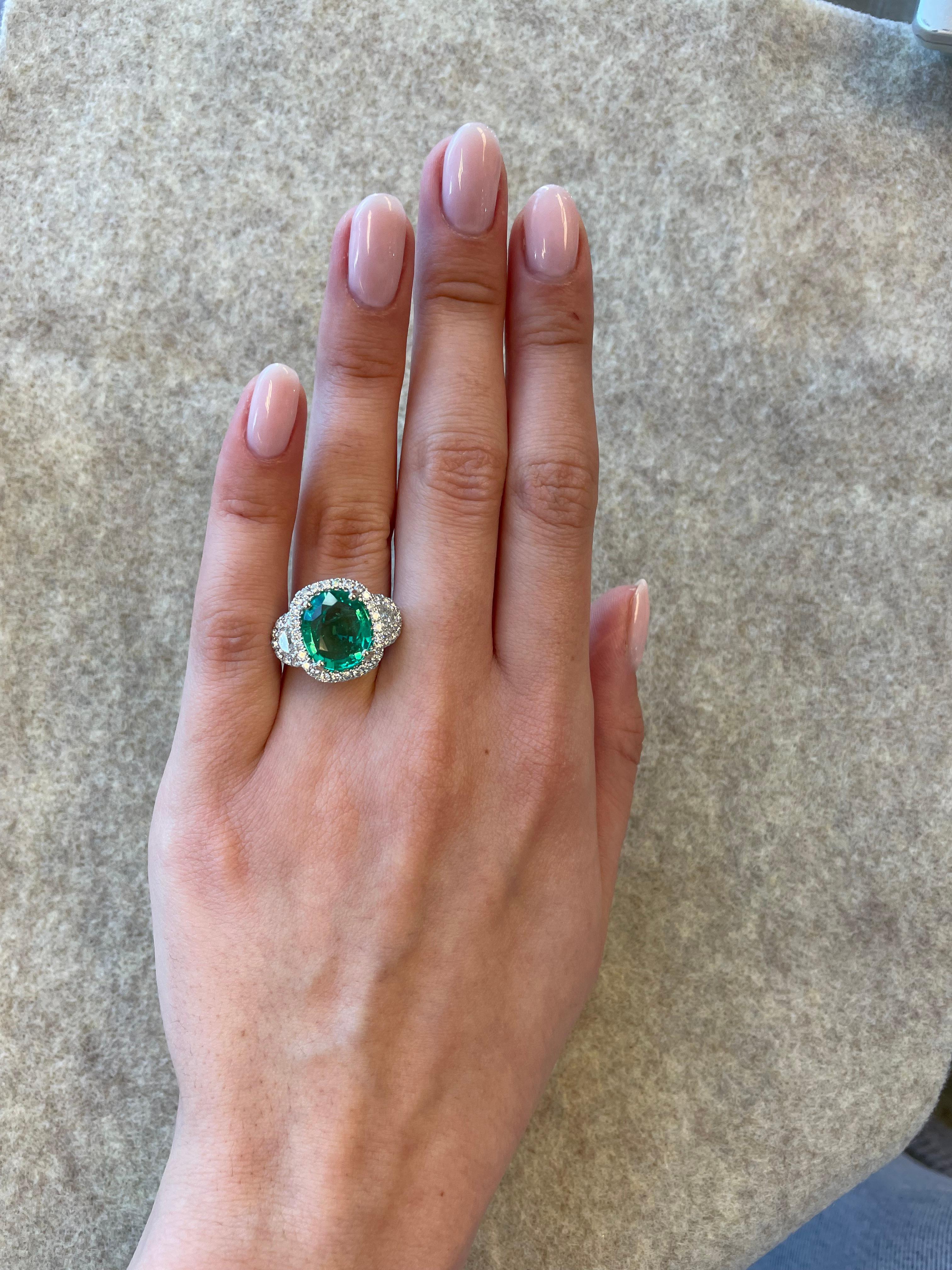Pretty emerald and diamond three stone ring with halo. 
4.94 carats total gemstone weight.
3.80 carat oval emerald. 2 half moons with 48 round brilliant diamonds. Approximately G/H color and VS-SI clarity. 18k white gold, current ring size 6.5.