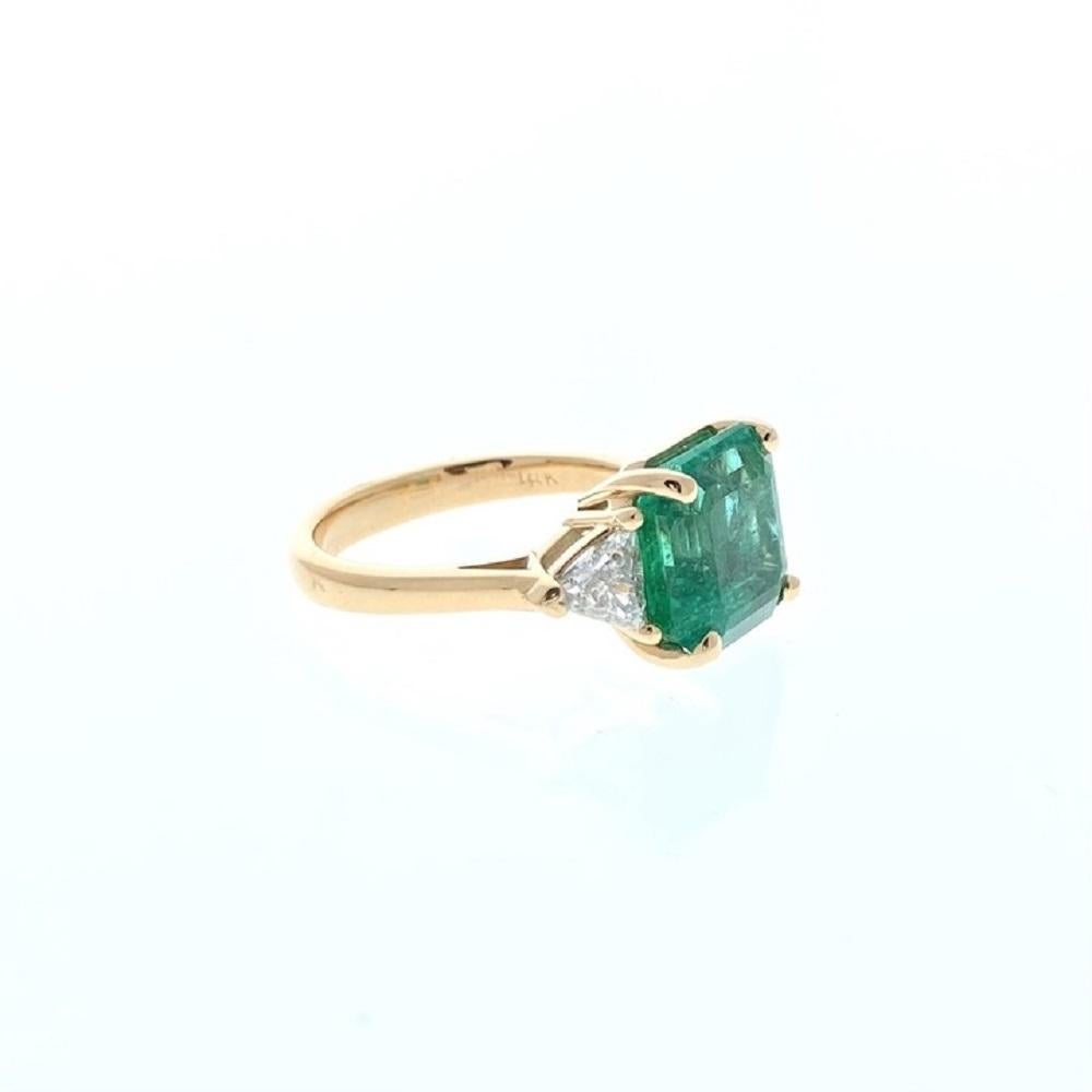A ring featuring a square emerald as the main stone with a weight of 4.95 carats. Additionally, there are two trilliant-cut diamonds serving as side stones, with a total carat weight of 1.24 carats. The setting for this ring is made of 18k yellow