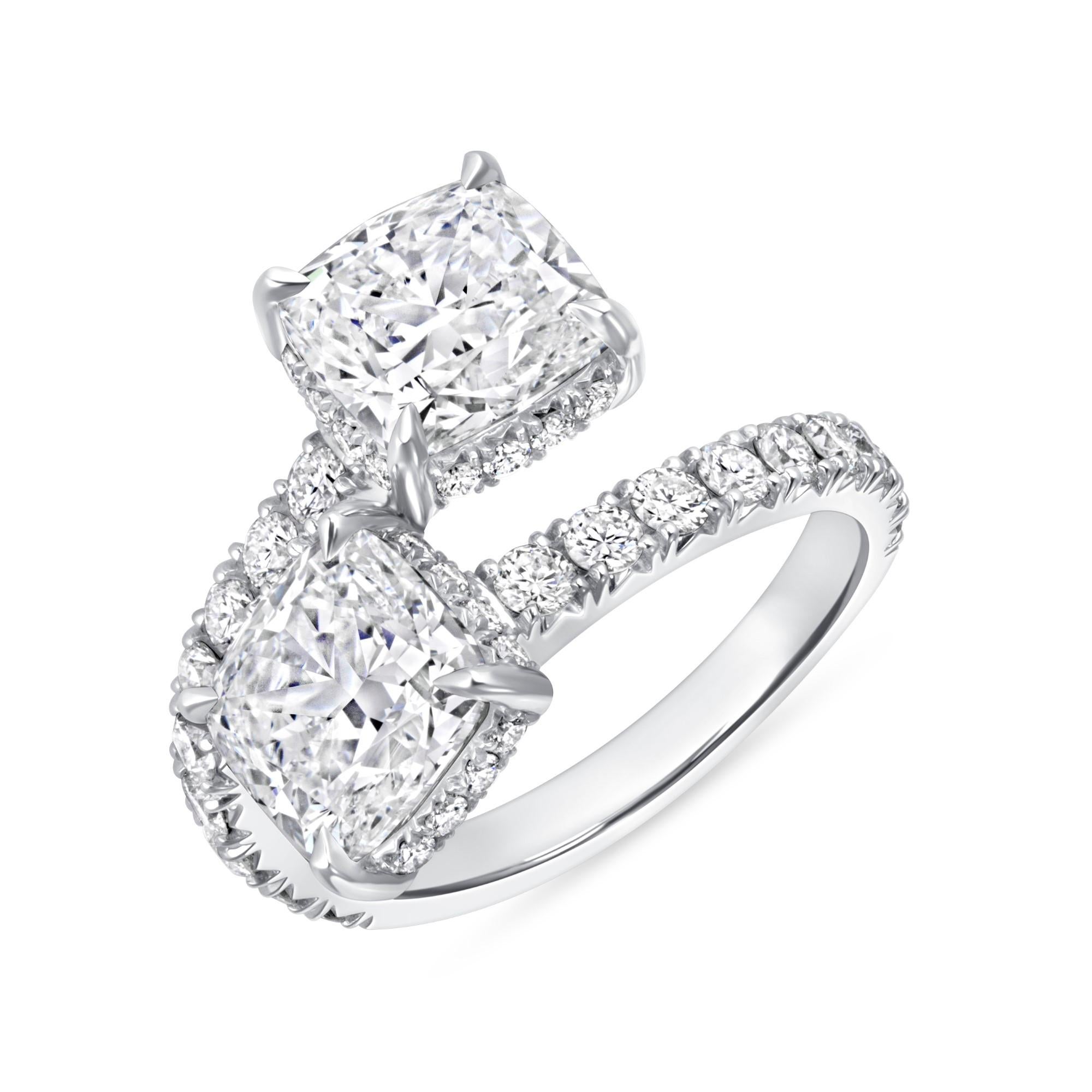 Cette bague en platine comporte deux diamants de taille coussin avec un halo caché et des diamants sertis en pavé.  Les deux diamants des deux extrémités sont certifiés GIA de couleur J et de pureté VS2-SI1.  La bague a un poids total de 4,96