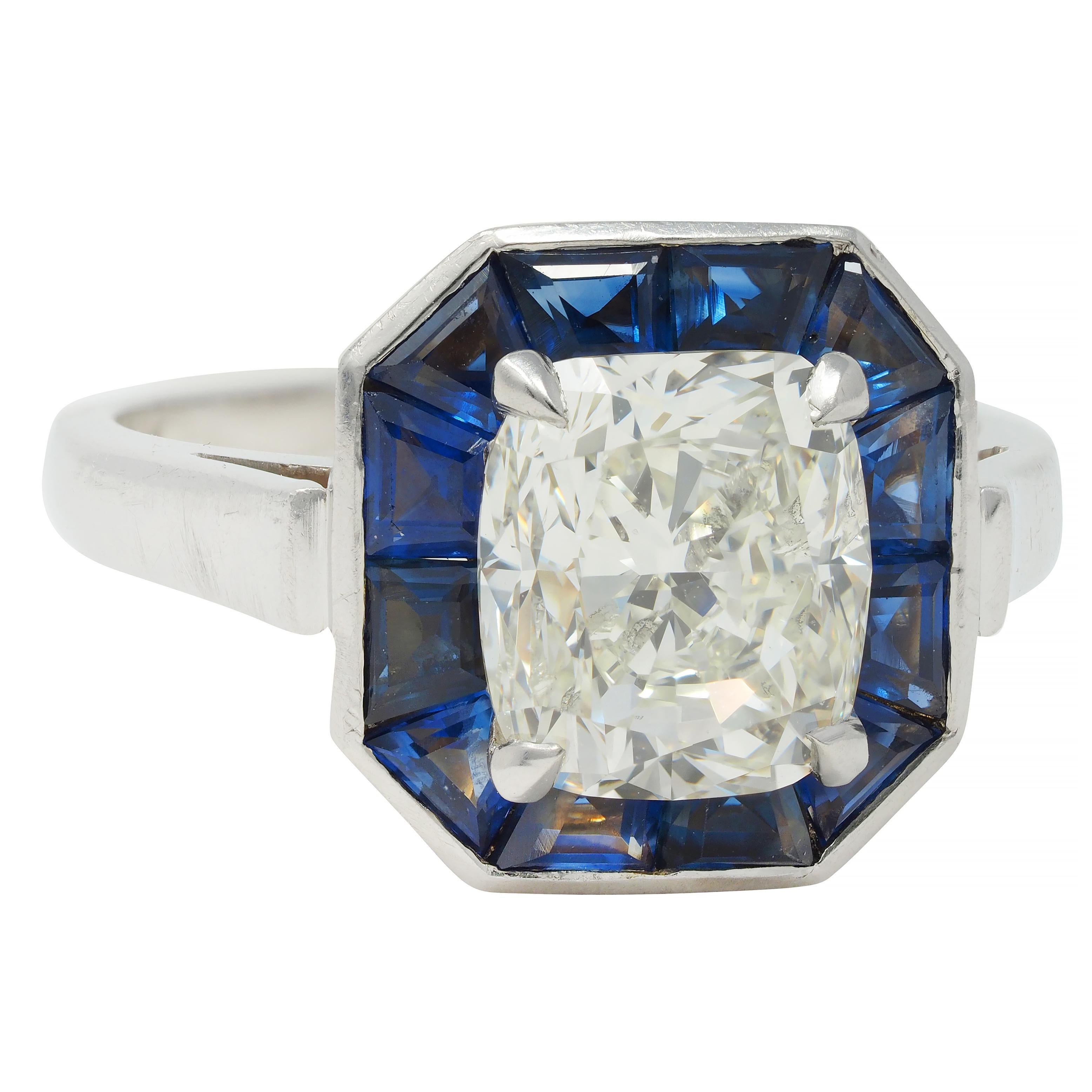 Centering an elongated cushion cut diamond weighing 2.81 carats total - L color with I1 clarity
Prong set with a recessed channel set halo surround of calibré cut sapphires 
Weighing approximately 2.16 carats total - transparent medium blue 
With a