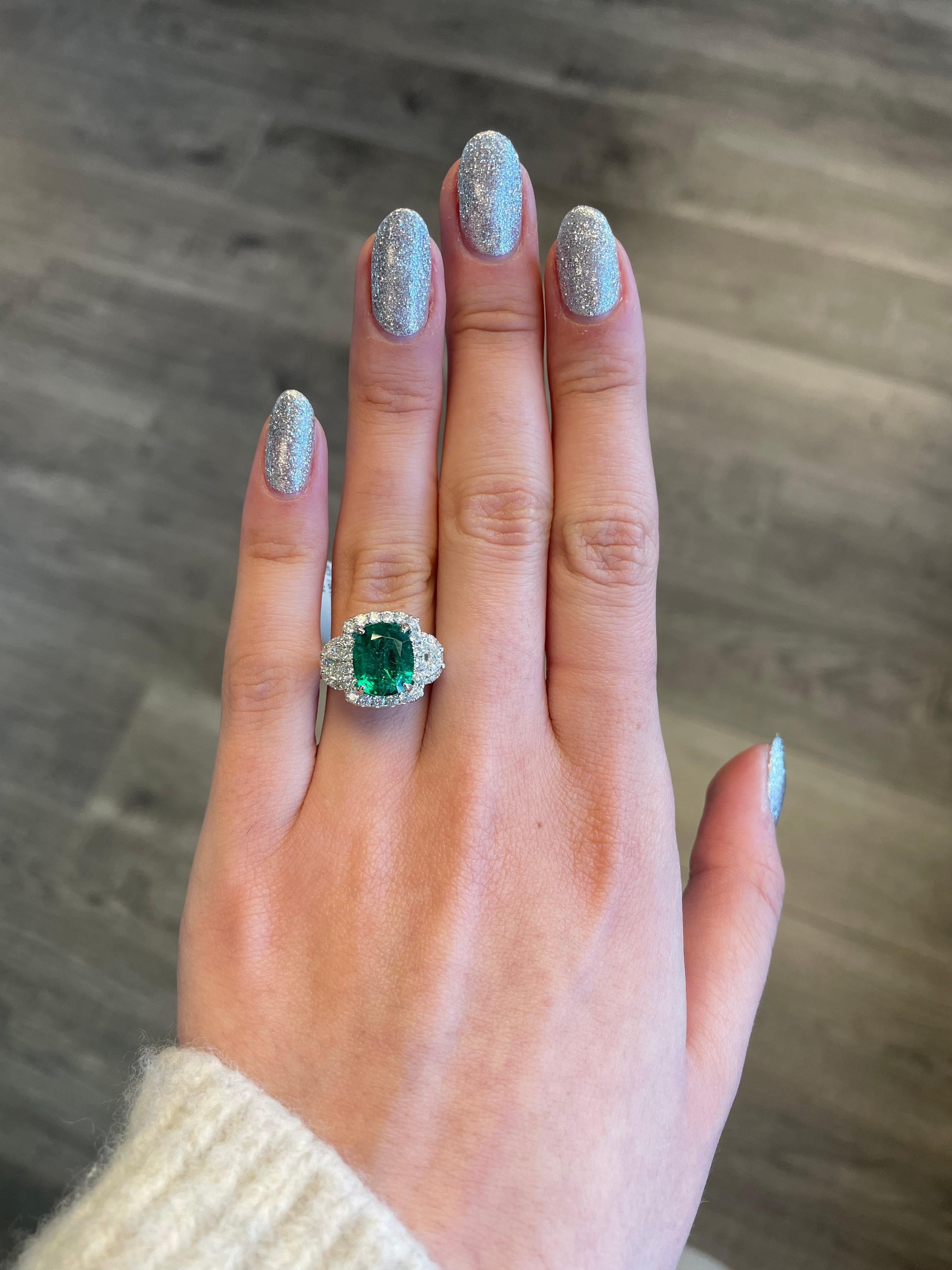 Stunning emerald and diamond three stone ring with halo. 
4.97 carats total gemstone weight.
3.63 carat cushion emerald, apx F2. 2 half moons with 58 round brilliant diamonds, 1.34 carats. Approximately G/H color and VS-SI clarity. 18k white gold,