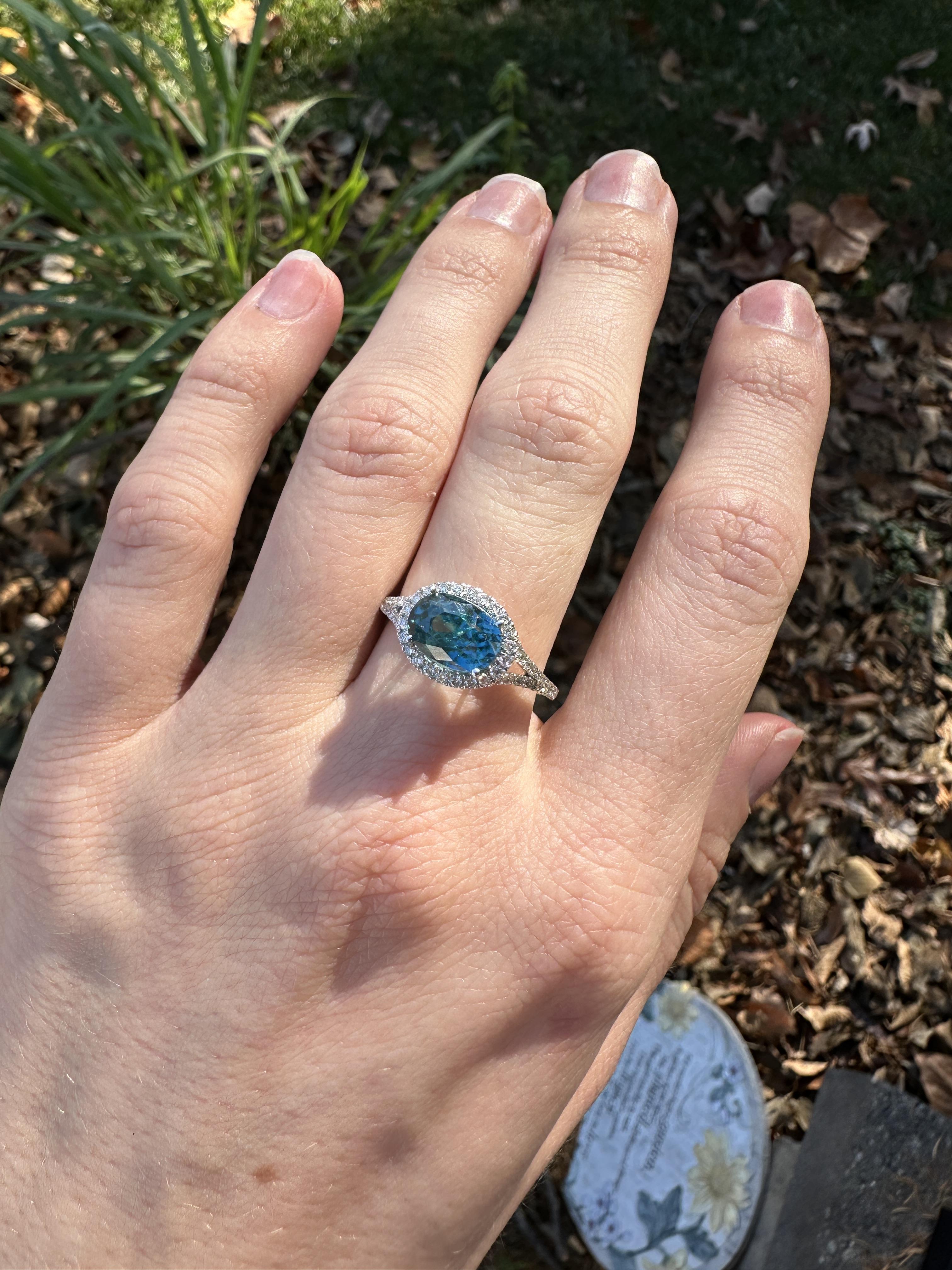 This beautiful ring features a sparkling 4.08 carat blue zircon in 14k white gold and natural earth mined diamond halo. A statement ring design is perfect for an eye-catching engagement or anniversary. This ring also makes a beautiful December